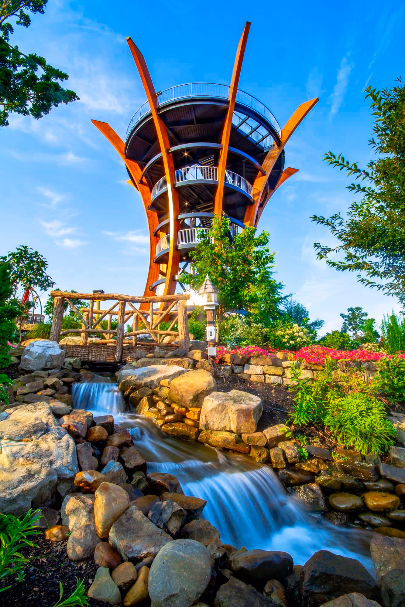 Modern tower with curved decks above a landscaped waterfall and stone stream at D&S Builders