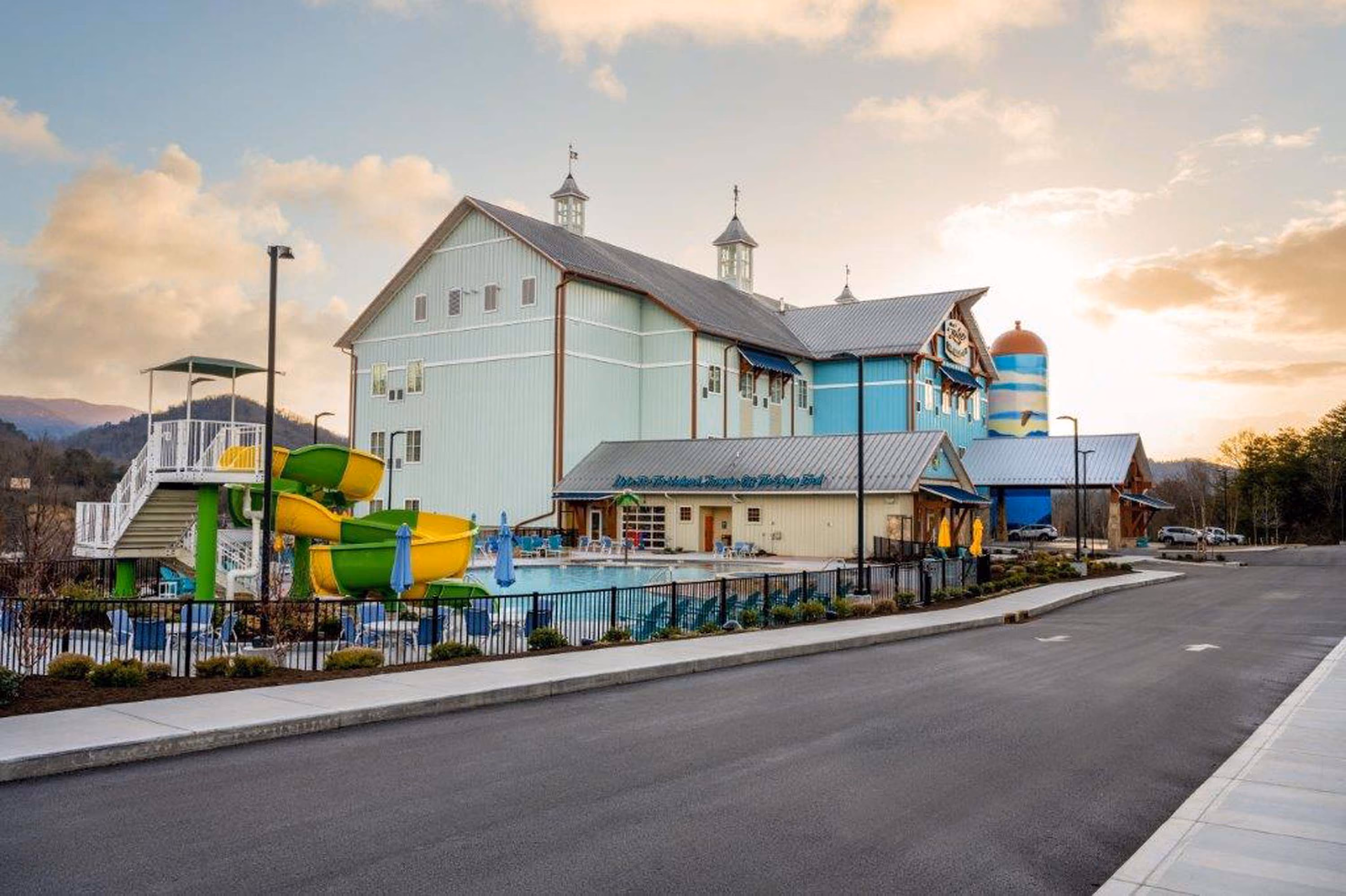 Waterpark resort building with colorful slides and an outdoor pool at sunset