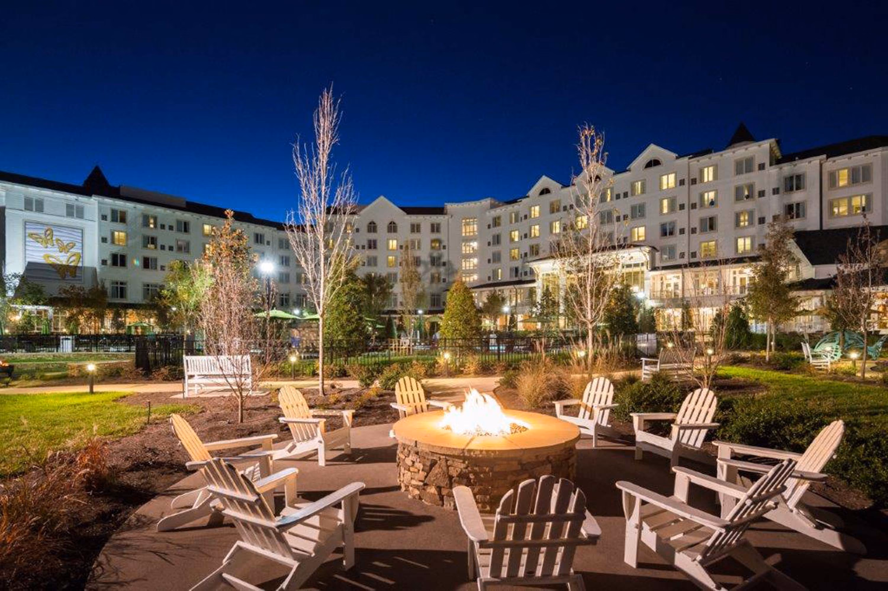 Hotel courtyard with fire pit and Adirondack chairs at night
