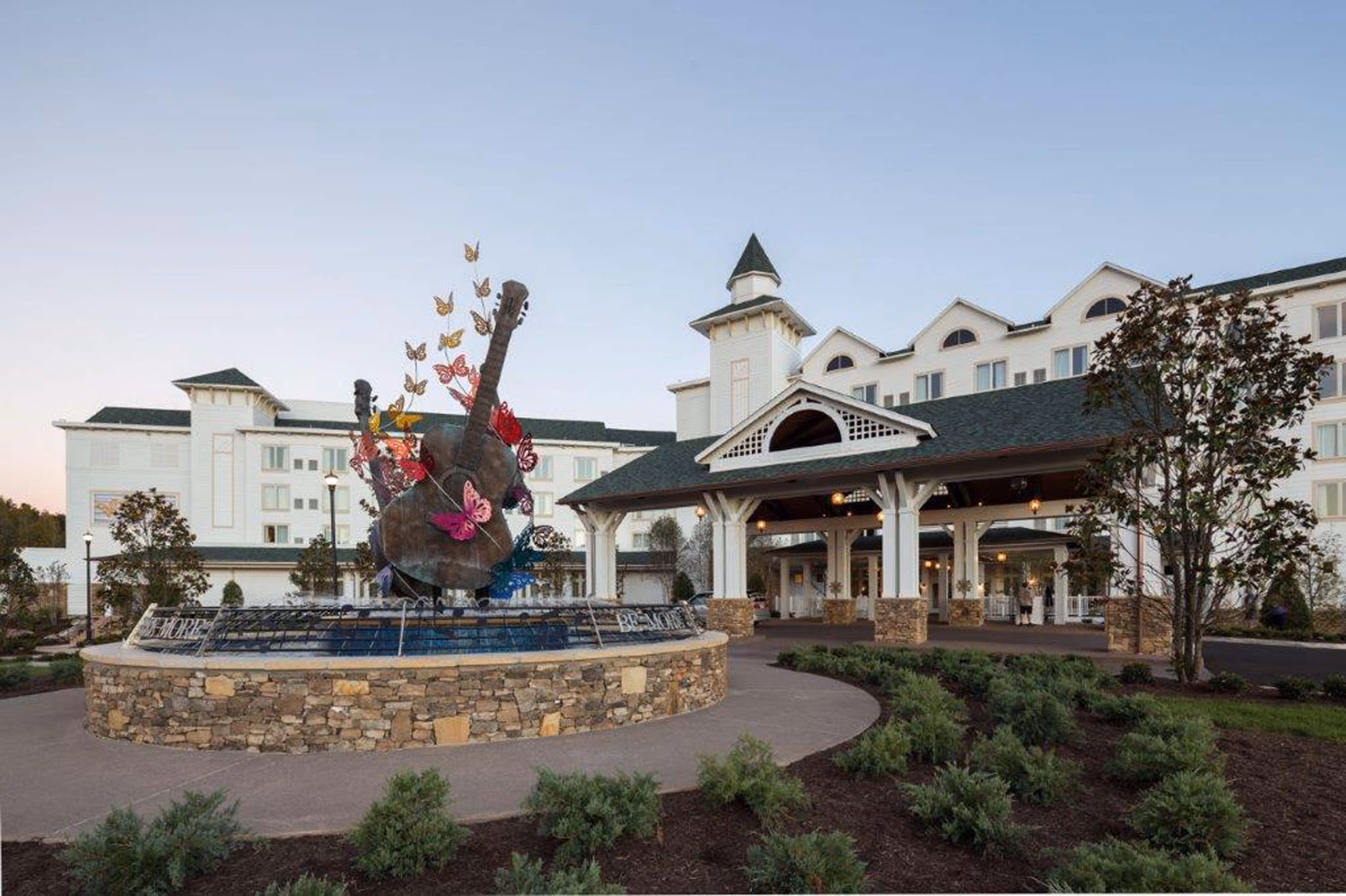 Hospitality building entrance with a guitar sculpture fountain and covered drop-off area