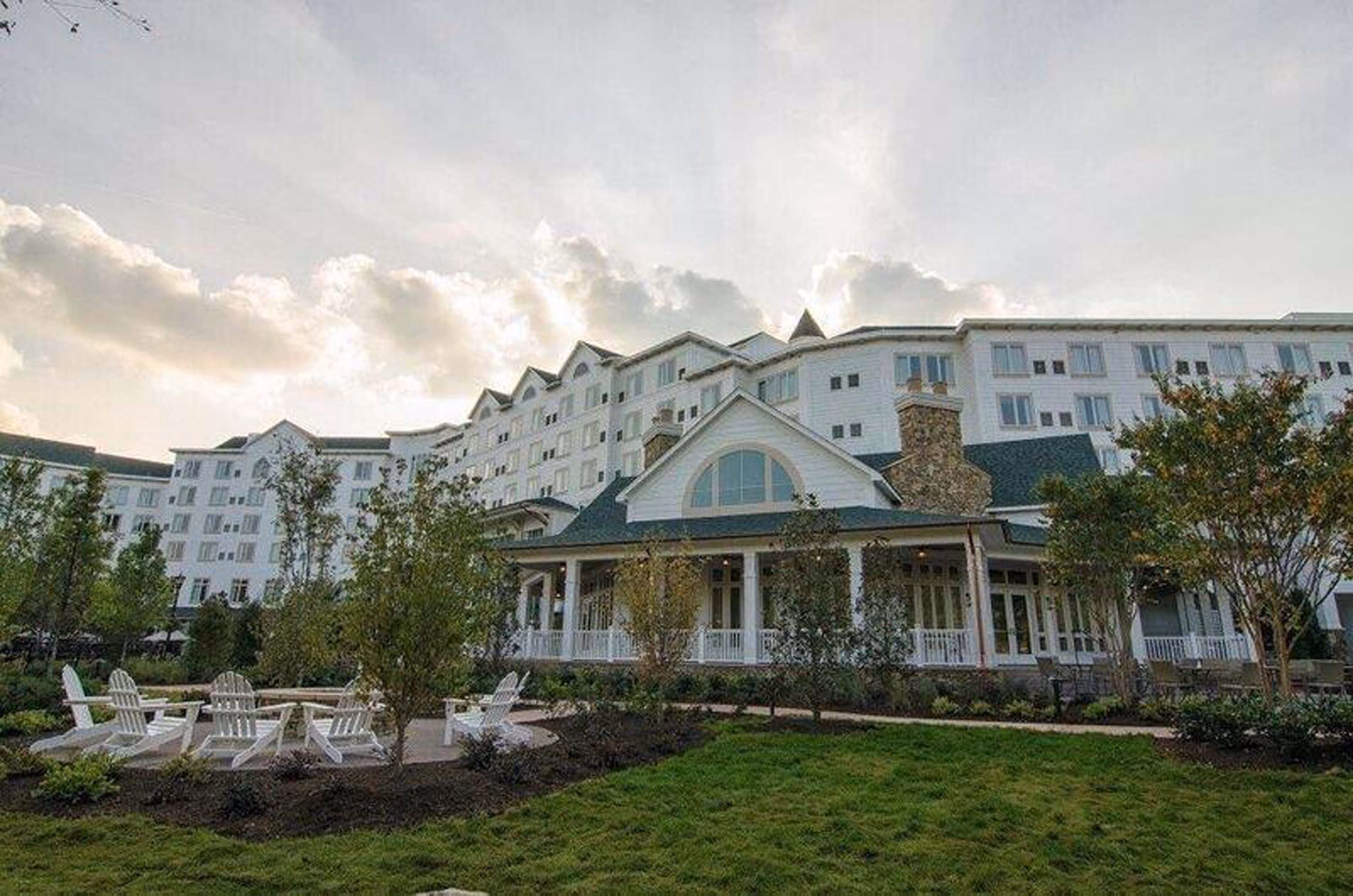 Large hospitality building with landscaped grounds and white Adirondack chairs