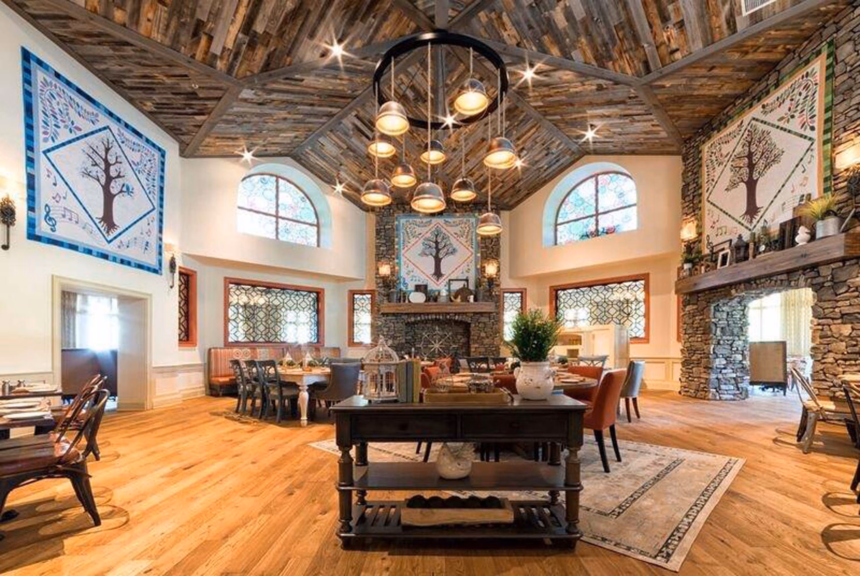 Rustic hospitality dining room with stone fireplace, wood ceiling, and hanging lights