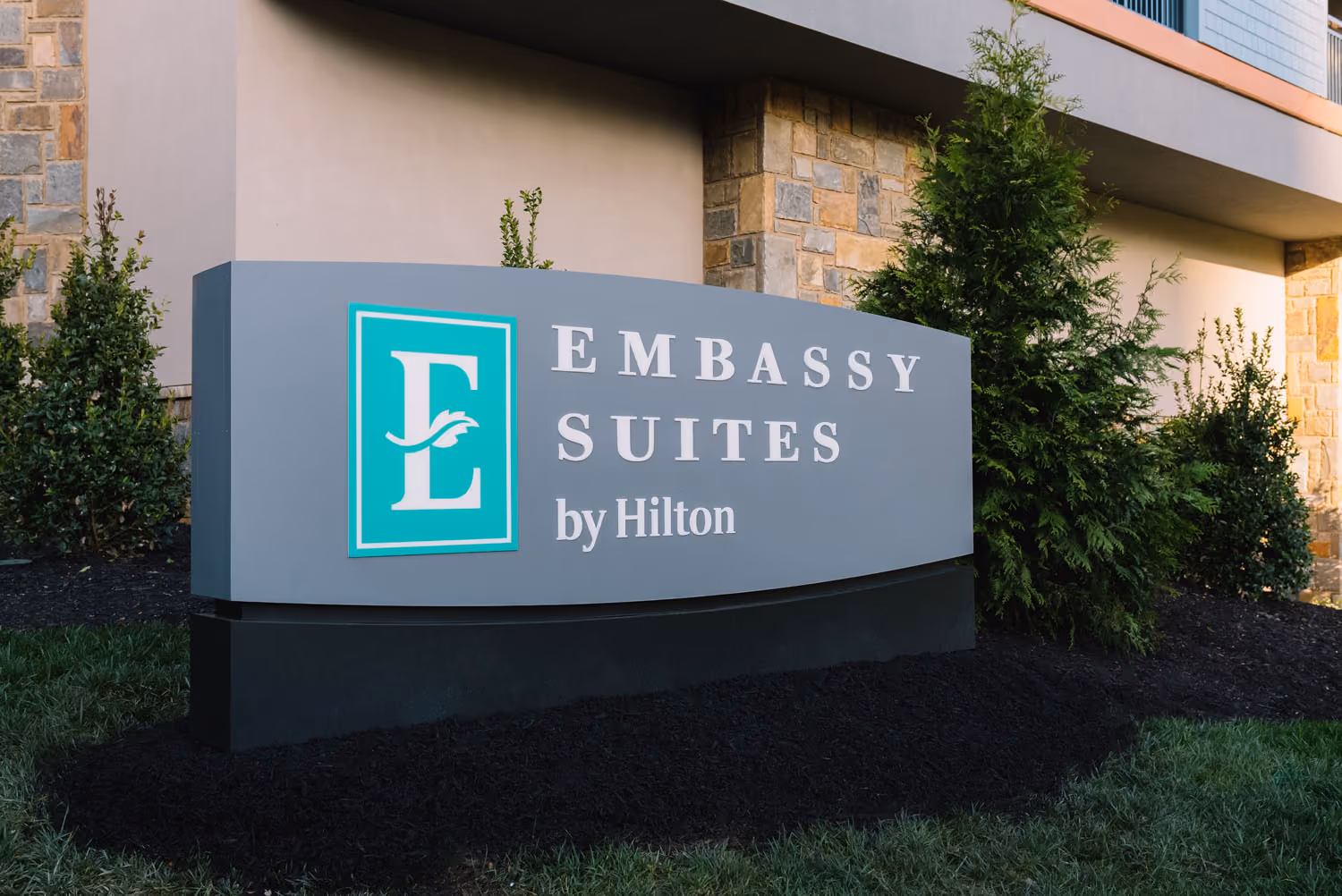 Embassy Suites by Hilton sign outside a hotel building with landscaping