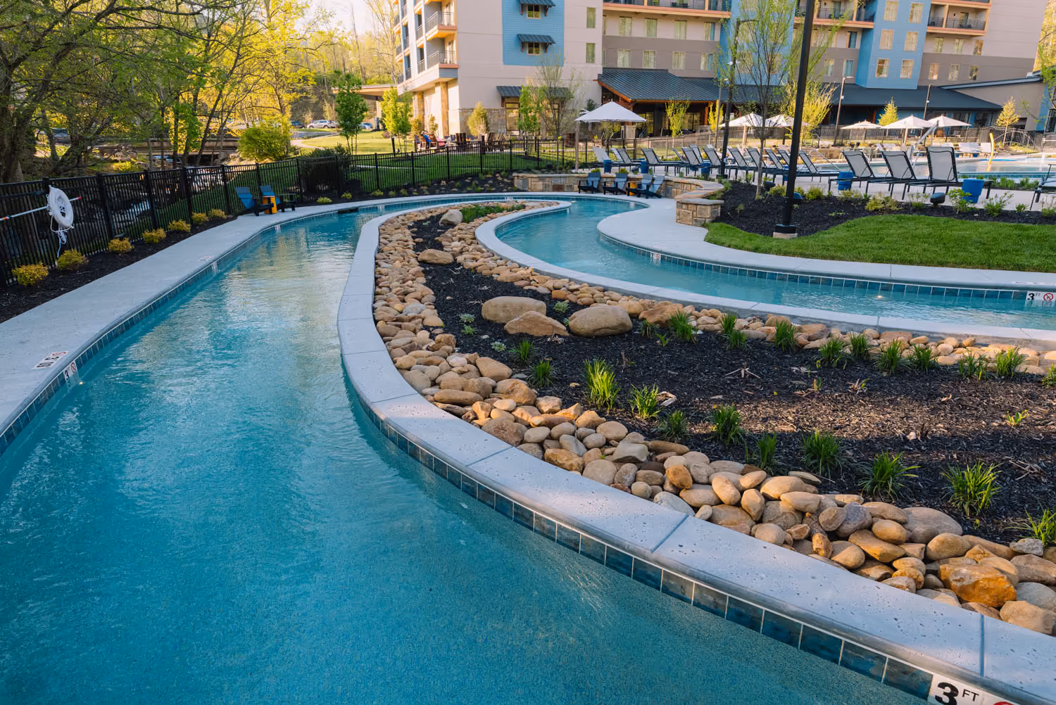 Curved resort-style pool with landscaped rock islands and lounge chairs at a hotel in Knoxville