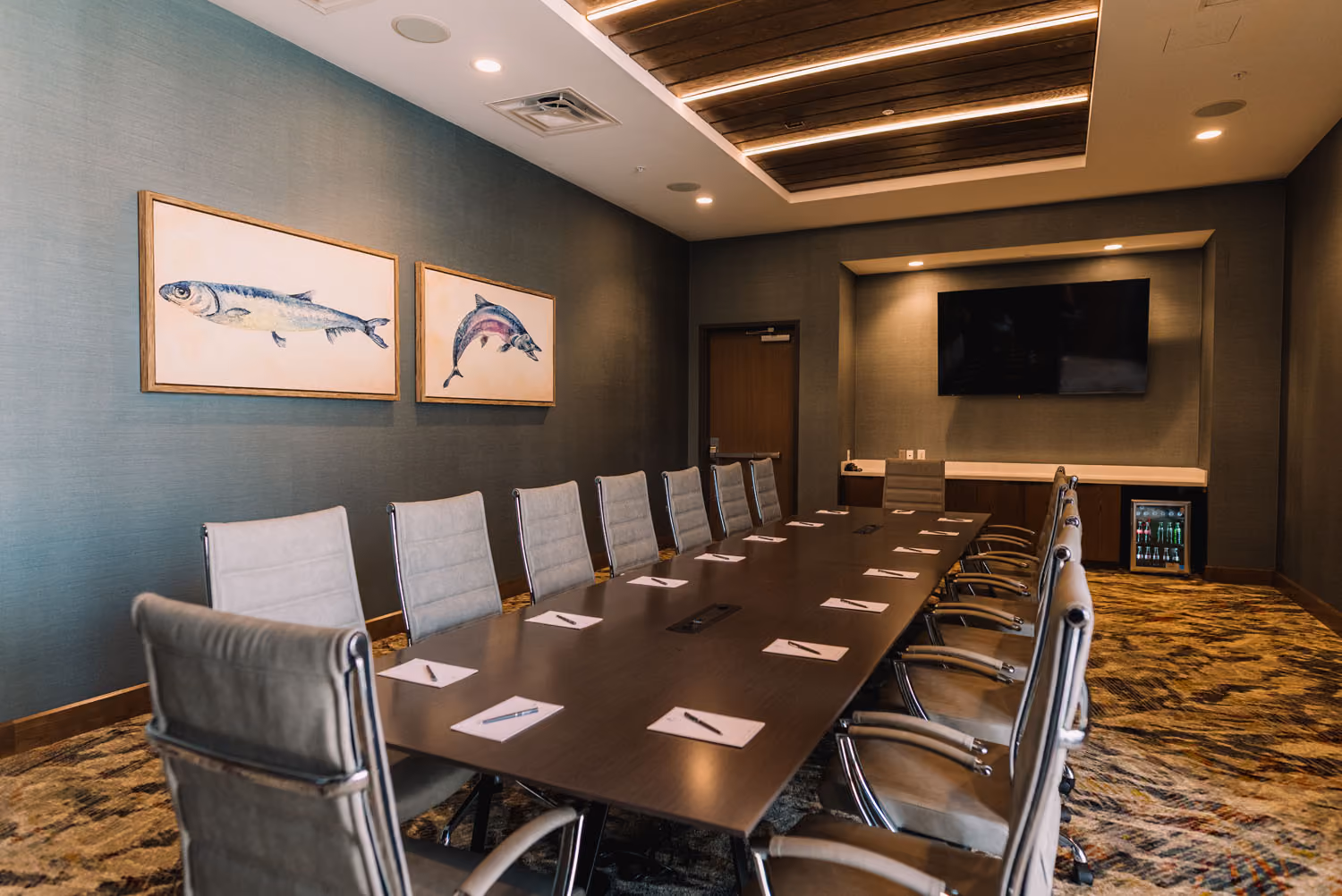 Modern conference room with long table, swivel chairs, wall art, and mounted TV