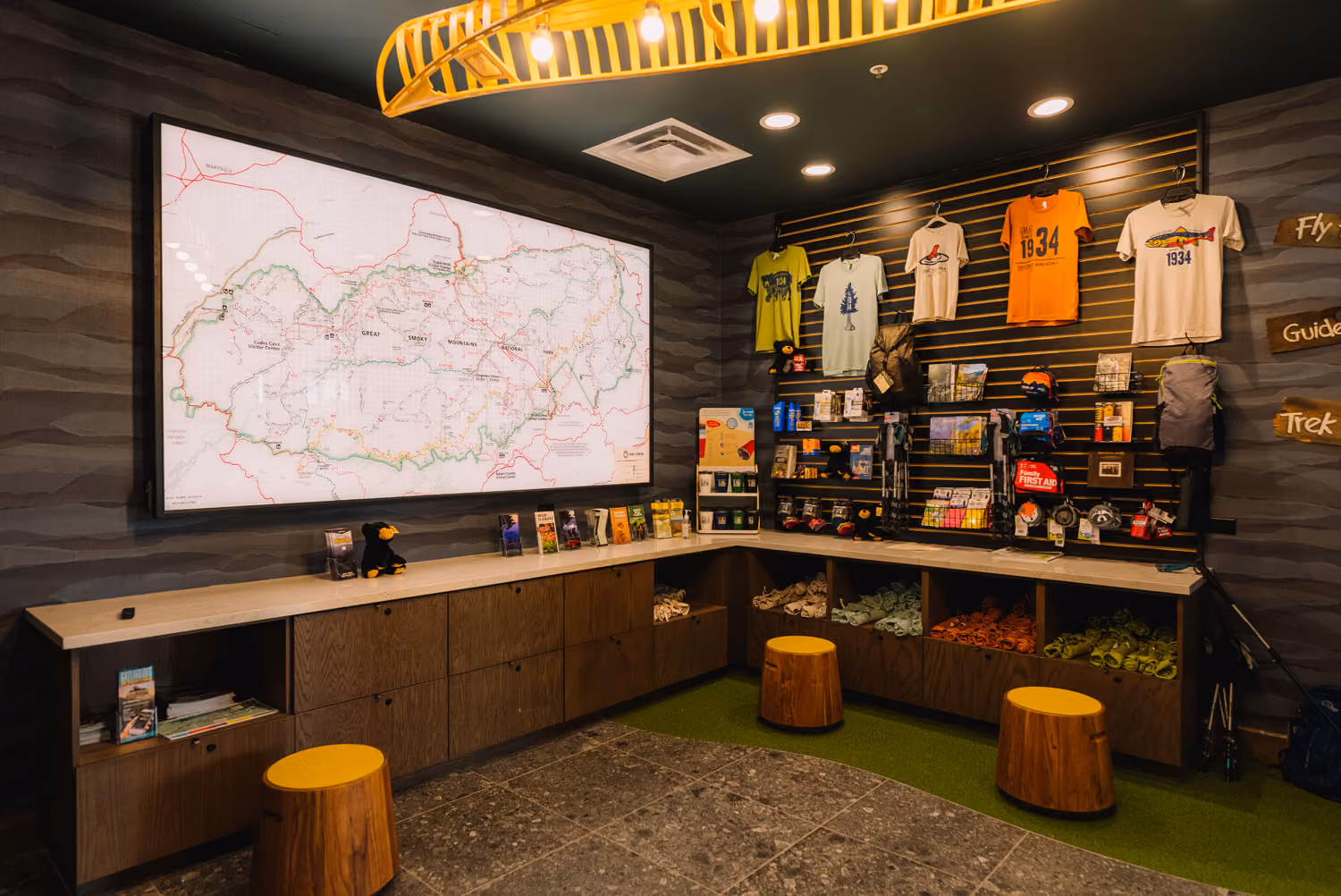 Retail display with trail map, outdoor gear, and T-shirts in a hospitality construction space