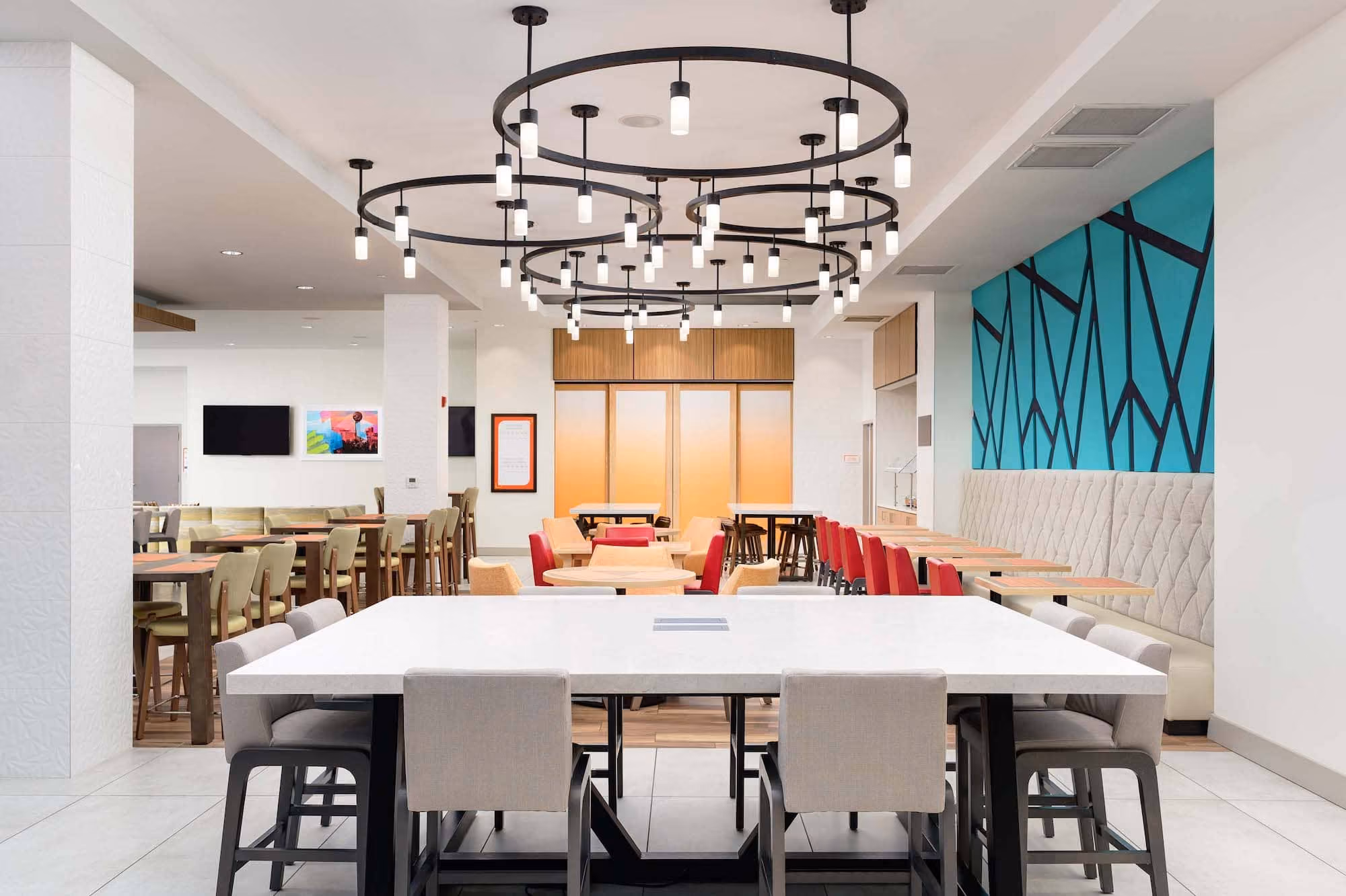 Modern hospitality dining area with circular pendant lights and colorful seating