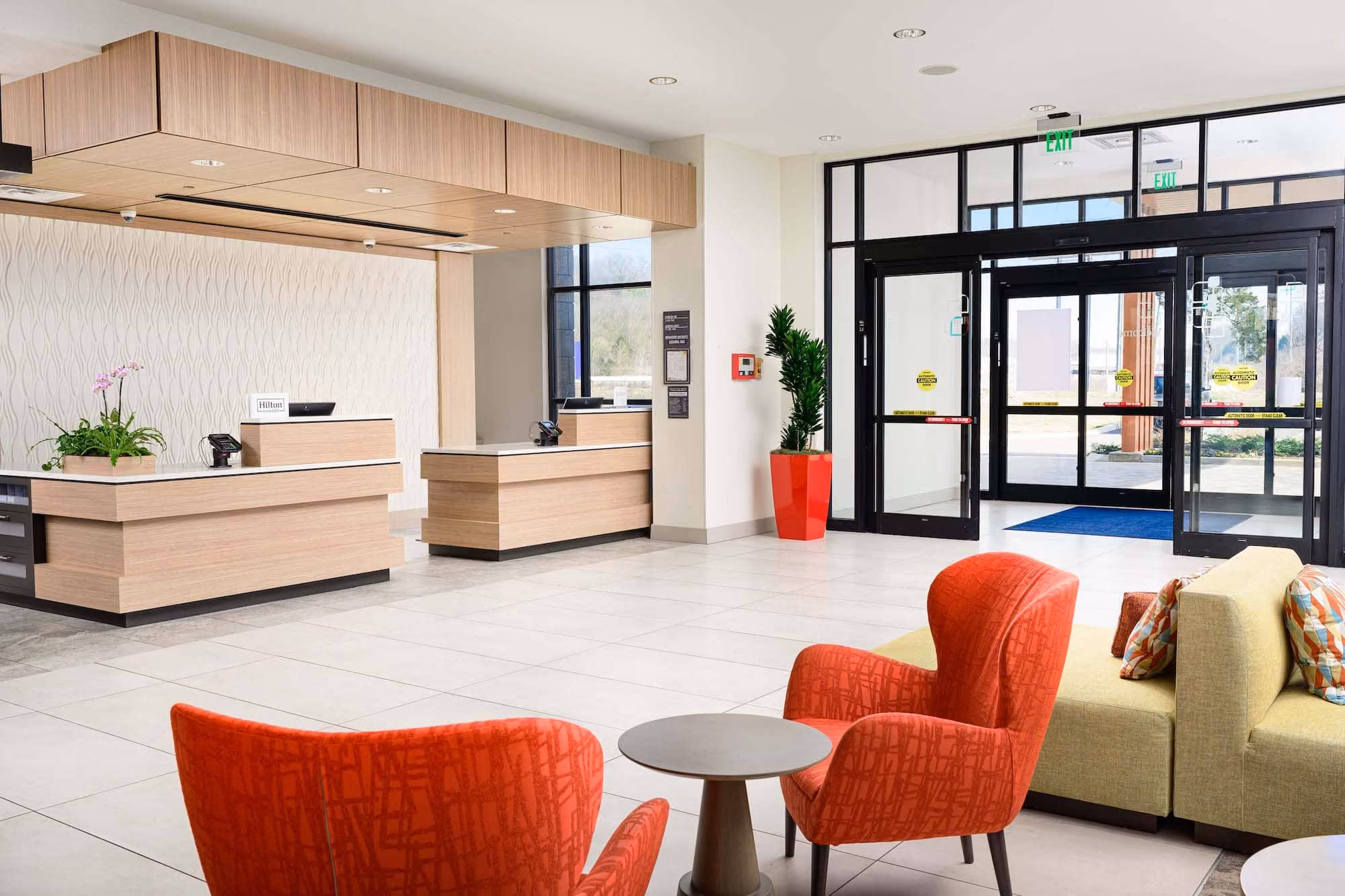 Modern hotel lobby with reception desks, seating, and glass entry doors