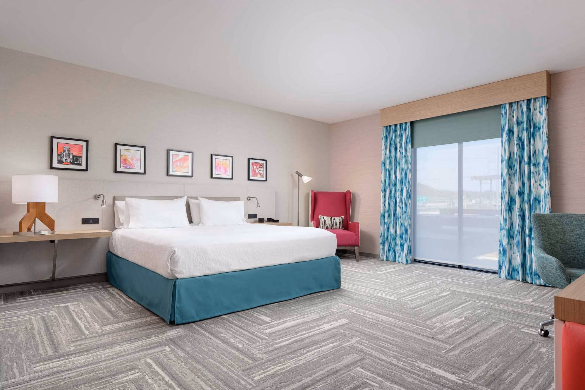 Modern hotel room with king bed, colorful chairs, and large window, likely hospitality construction by D&S Builders