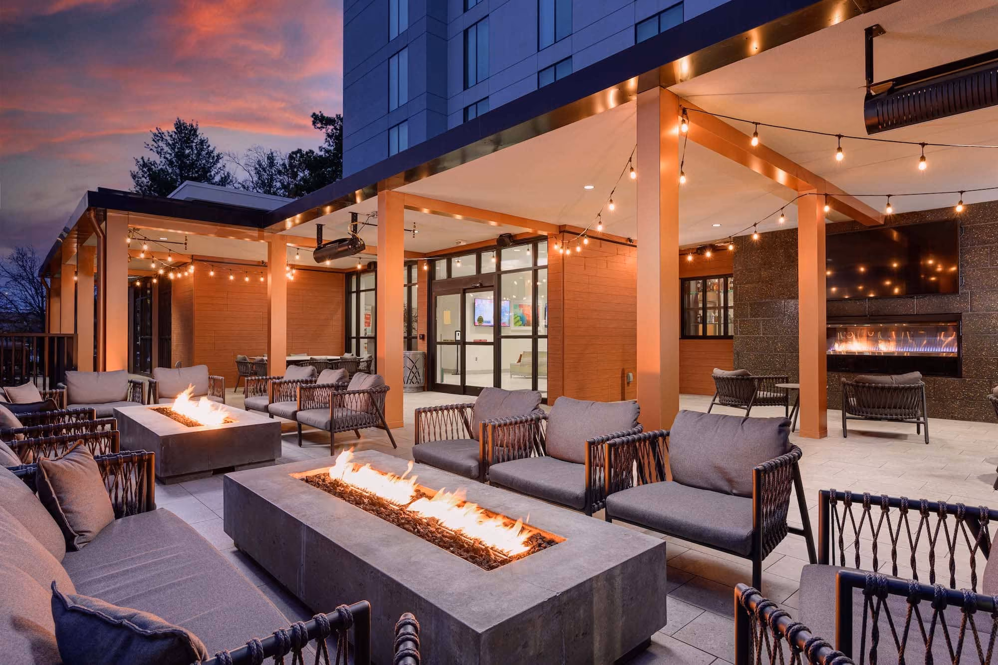 Covered hospitality patio with fire pits, string lights, and lounge seating at D&S Builders