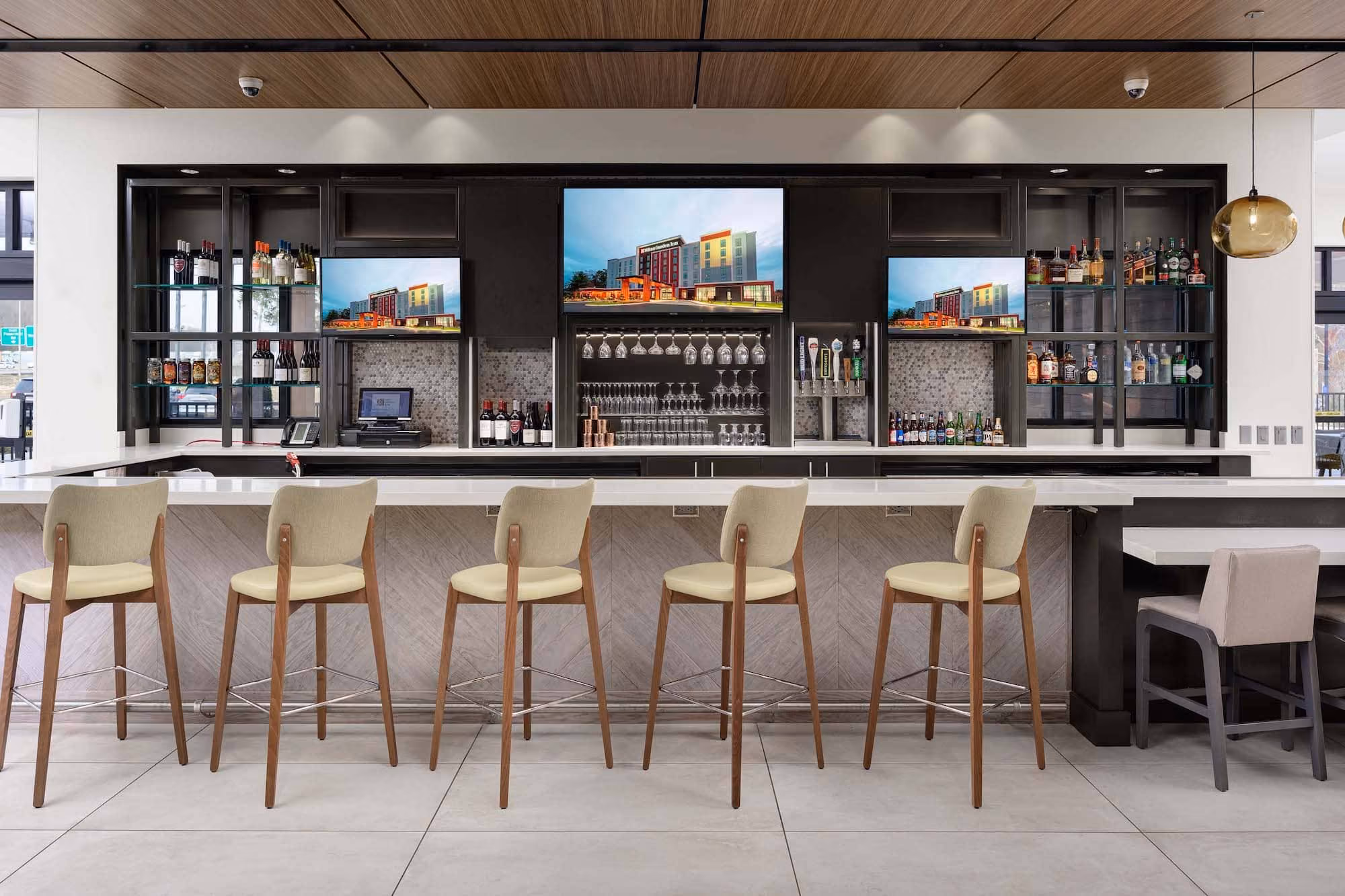 Modern hotel bar with stools and backlit liquor shelves, showcasing D&S Builders hospitality construction.