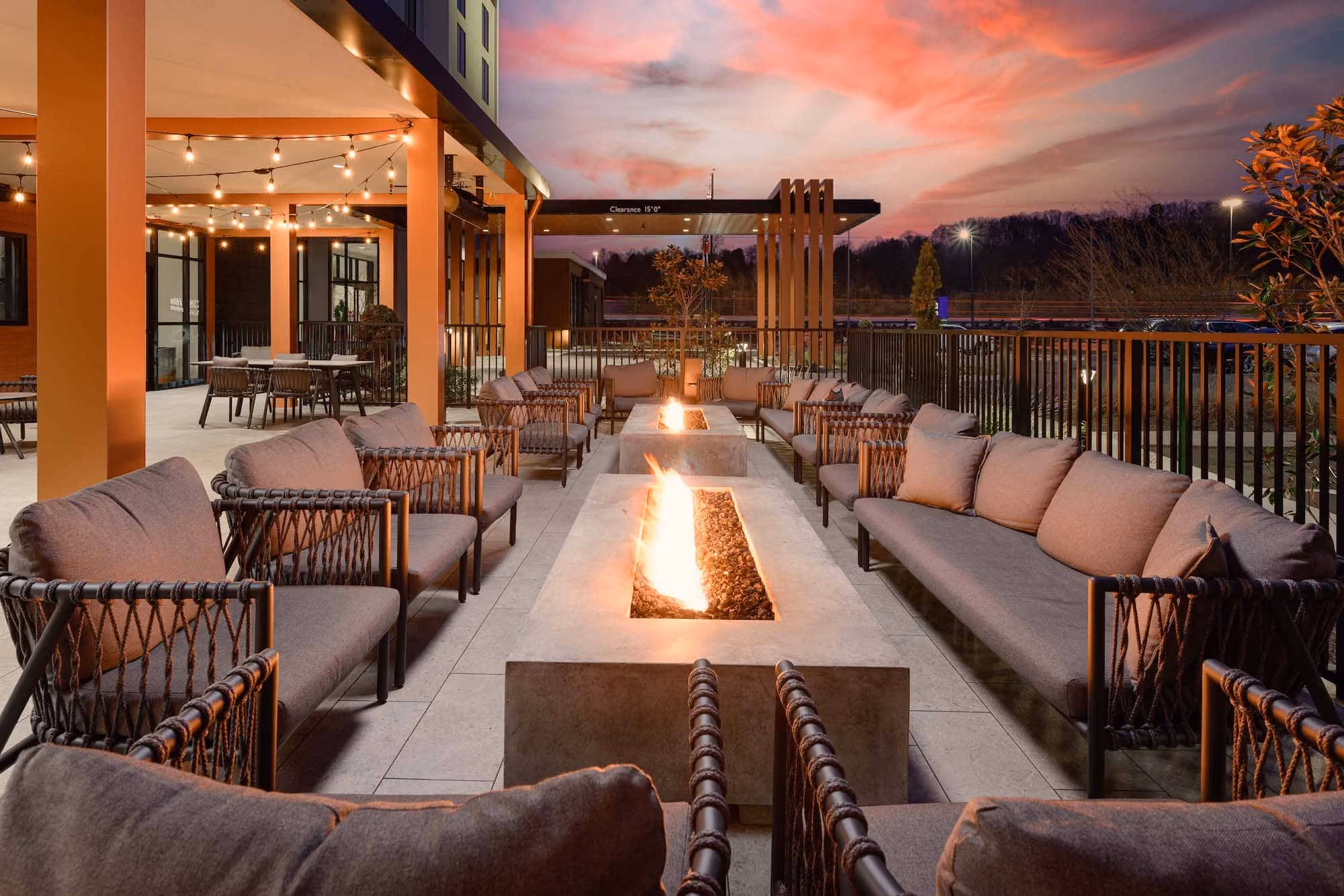 Outdoor hospitality patio with fire pit and cushioned seating at dusk