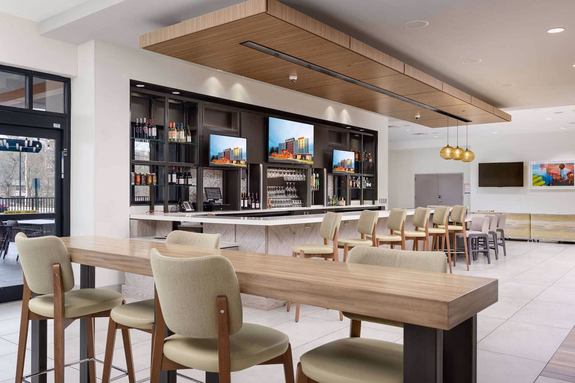 Modern hotel bar and lounge seating area with wood tables and backlit shelves, D&S Builders hospitality construction
