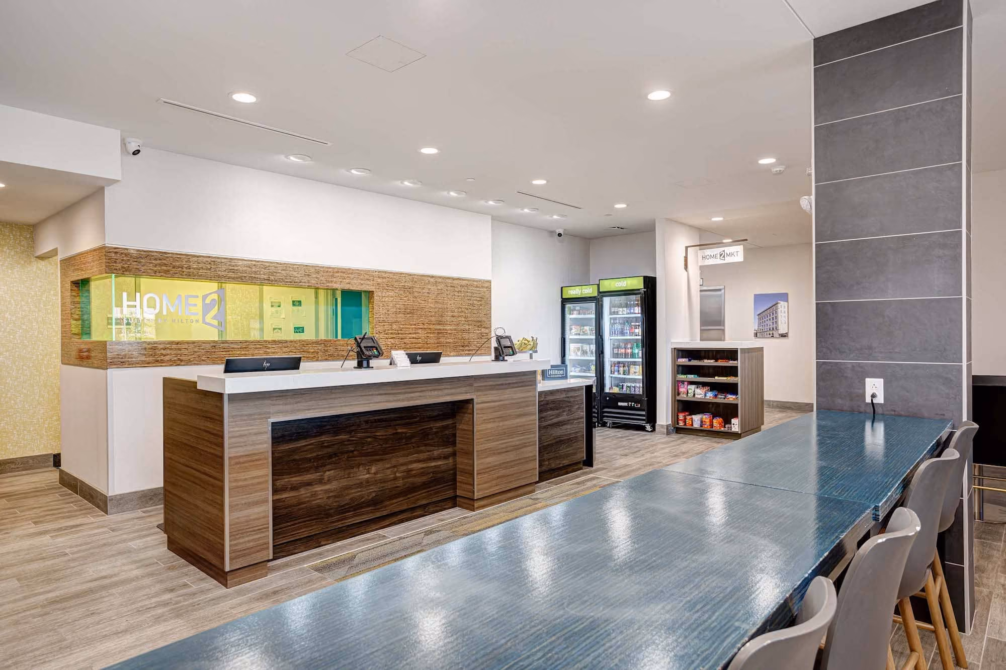 Modern hotel lobby with front desk, beverage coolers, and seating area