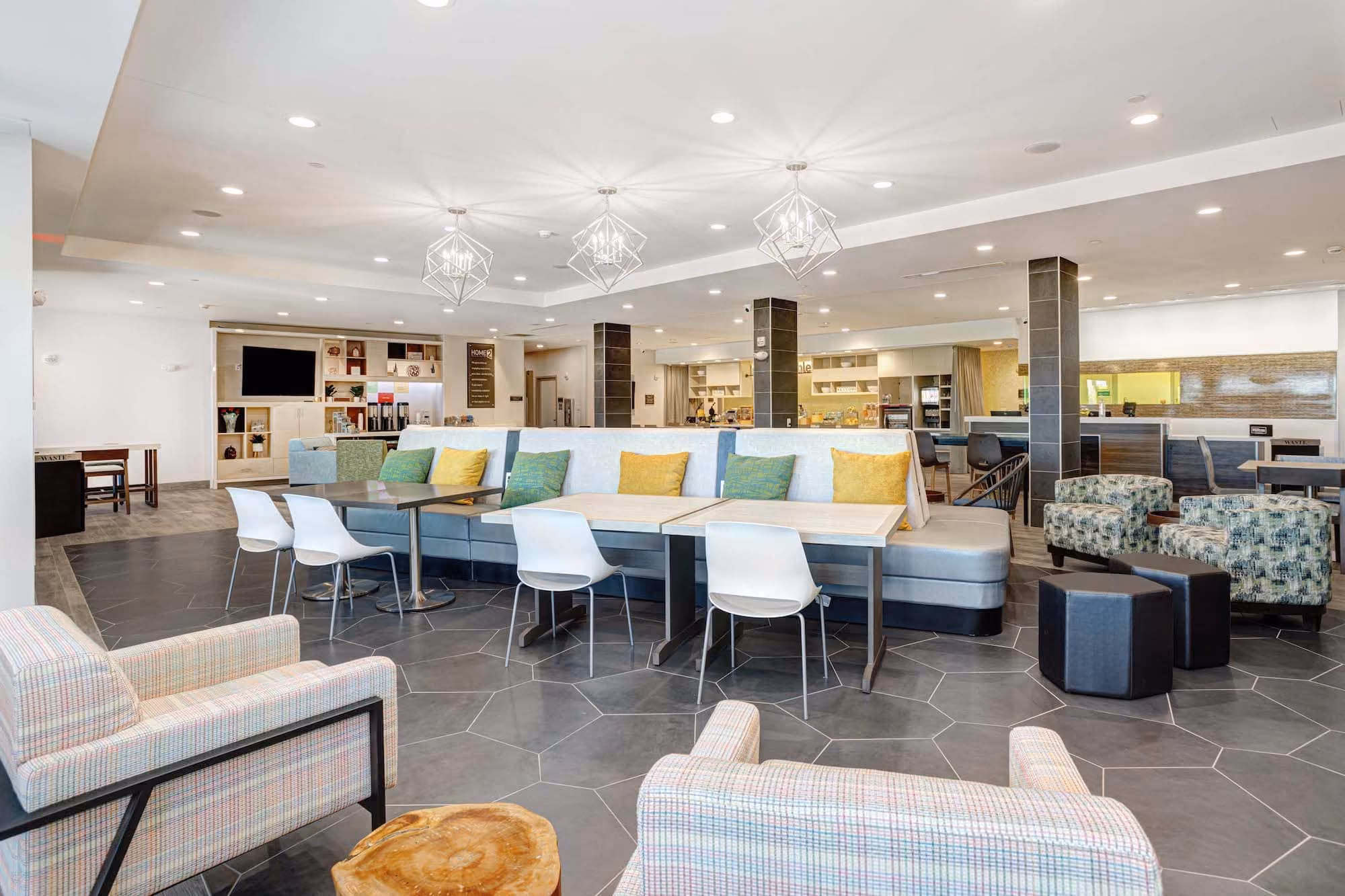 Modern hotel lobby seating area with tables, lounge chairs, and pendant lights by D&S Builders