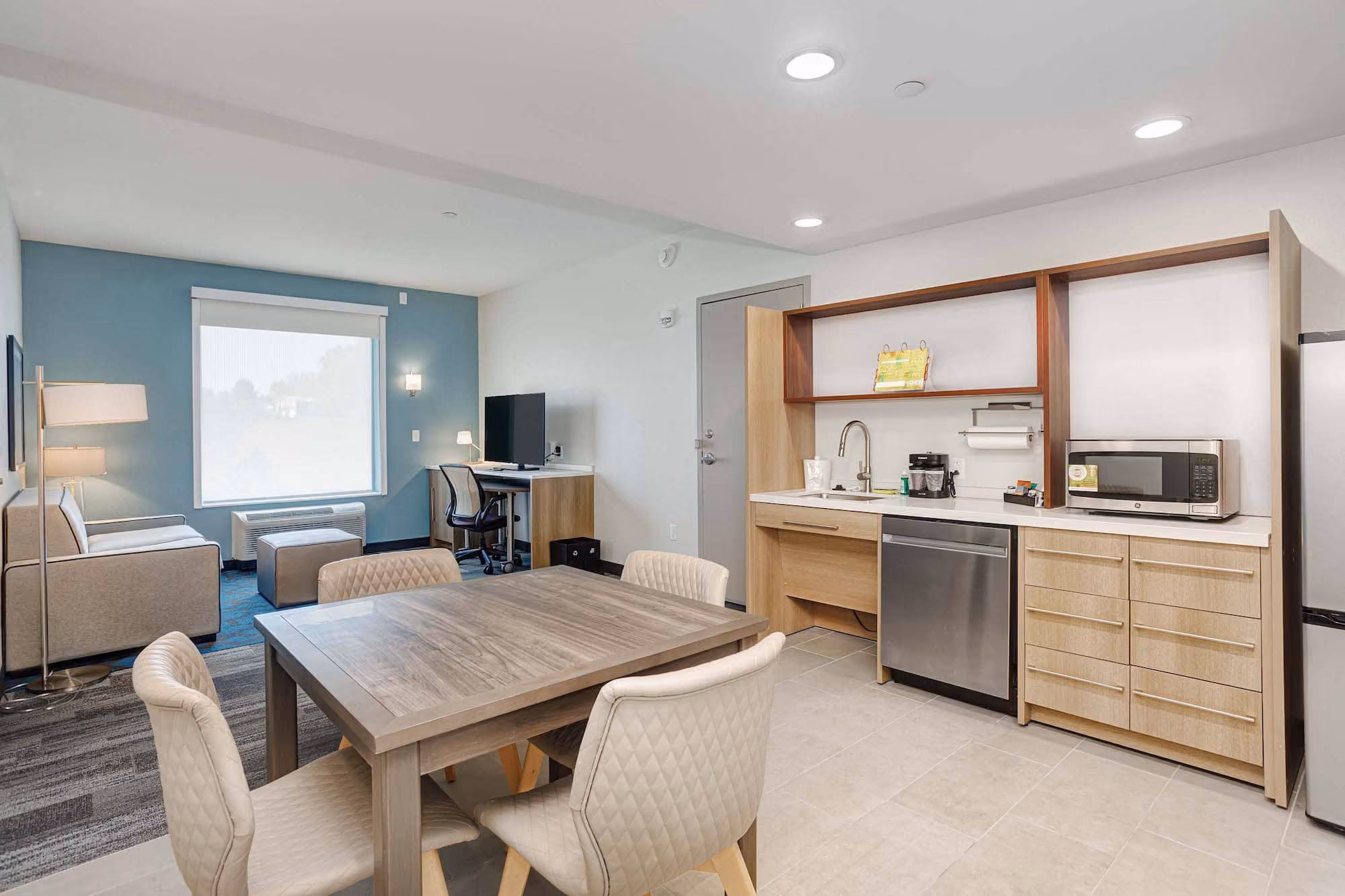 Modern hospitality suite with dining table, kitchenette, and workspace