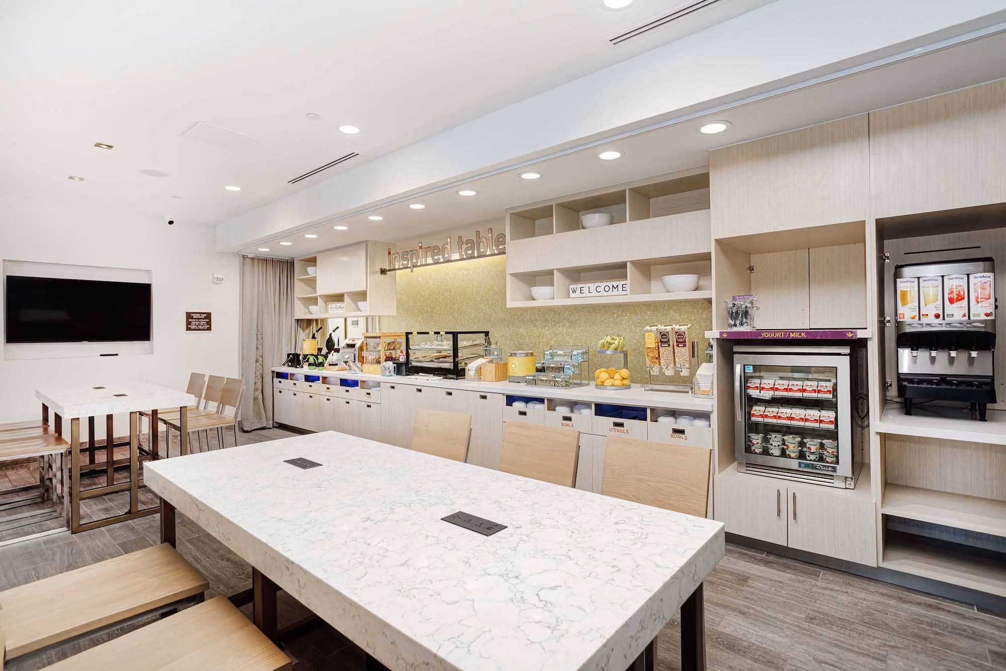Modern hotel breakfast area with tables, buffet counter, and beverage station by D&S Builders