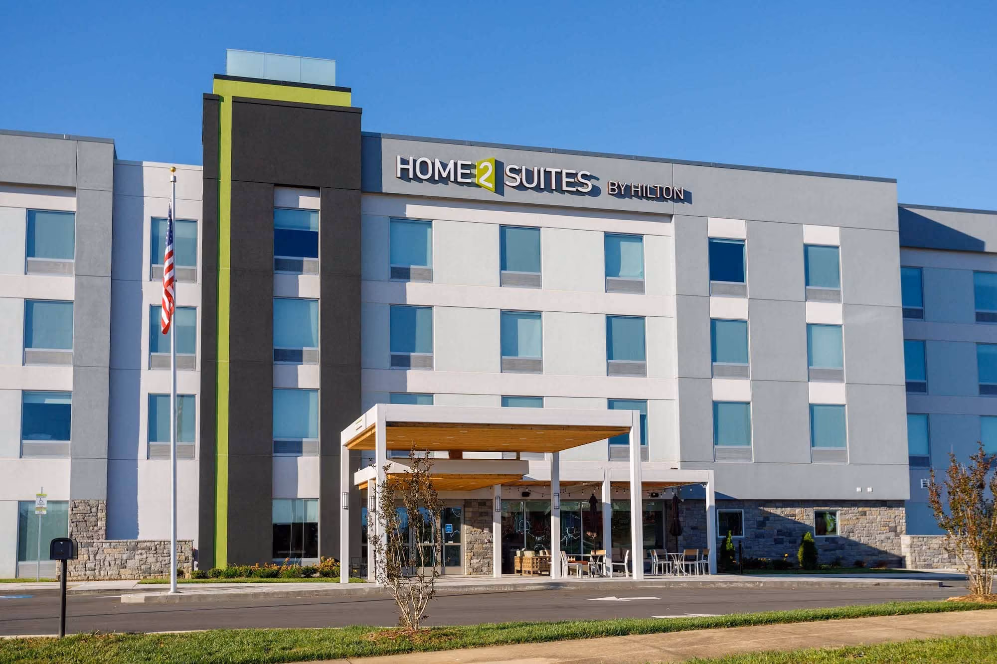 Home2 Suites by Hilton hotel exterior with flagpole and covered entrance