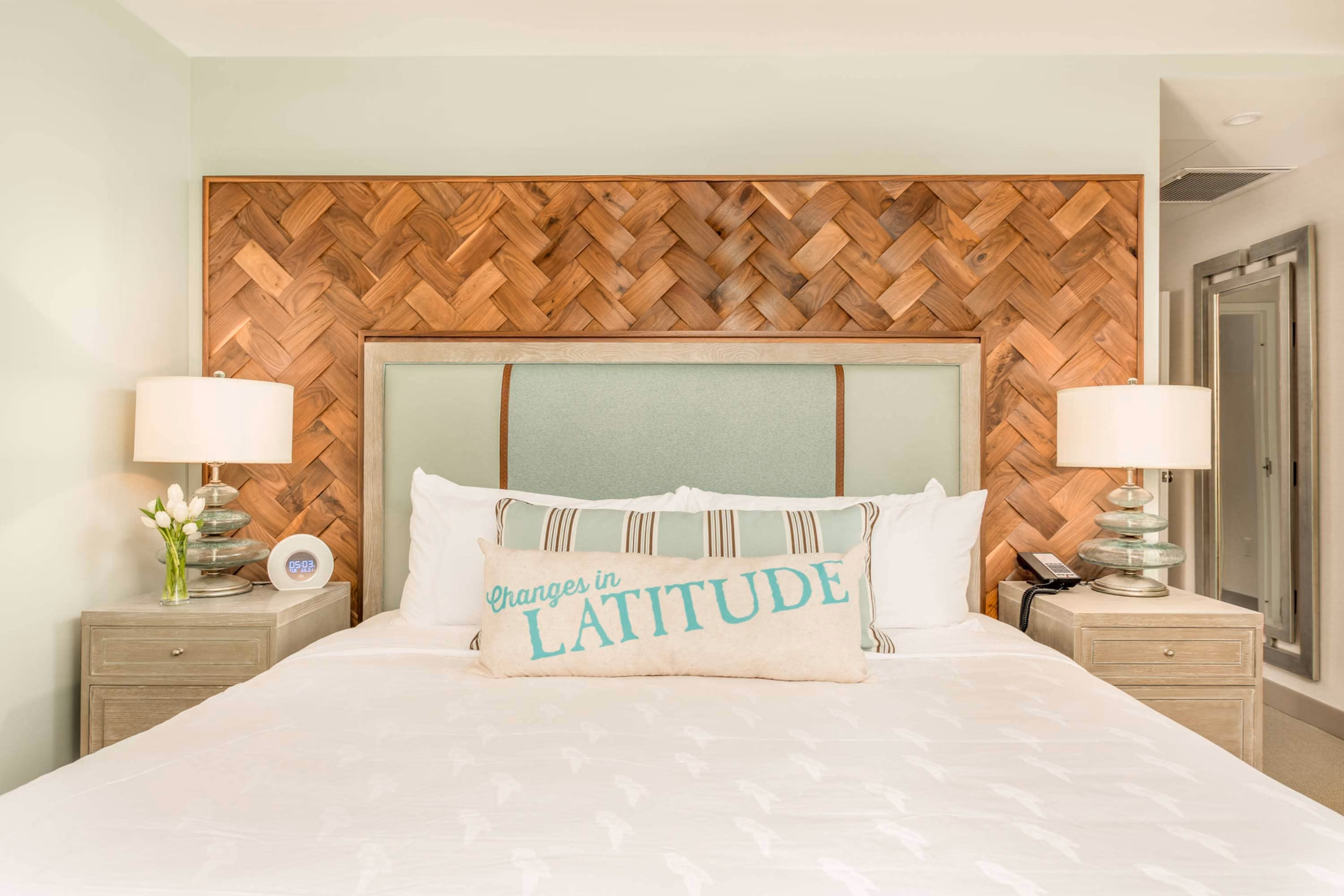 Stylish hotel bedroom with woven wood headboard and bedside lamps, D&S Builders hospitality construction
