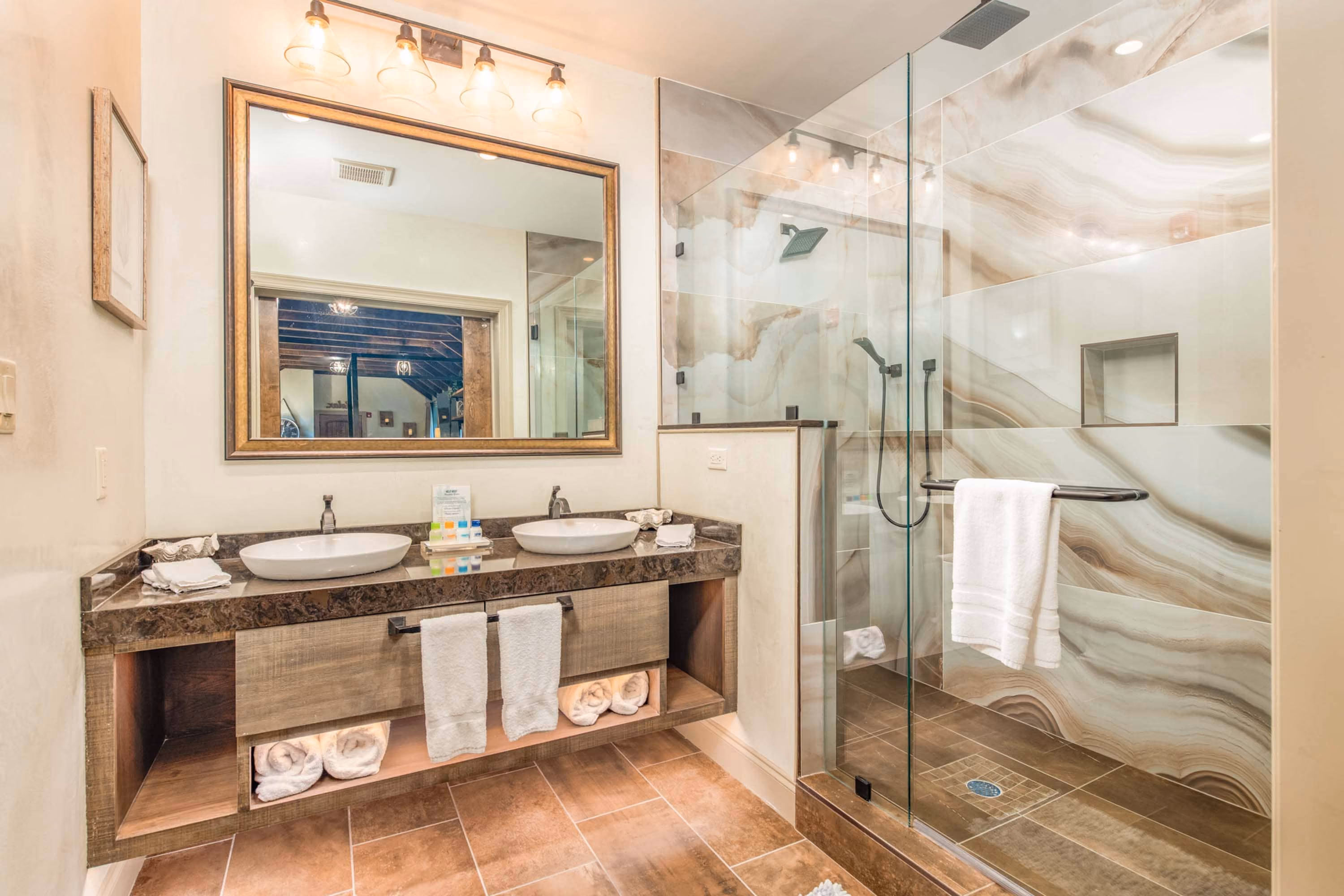 Modern bathroom with double vanity, large mirror, and glass shower enclosure