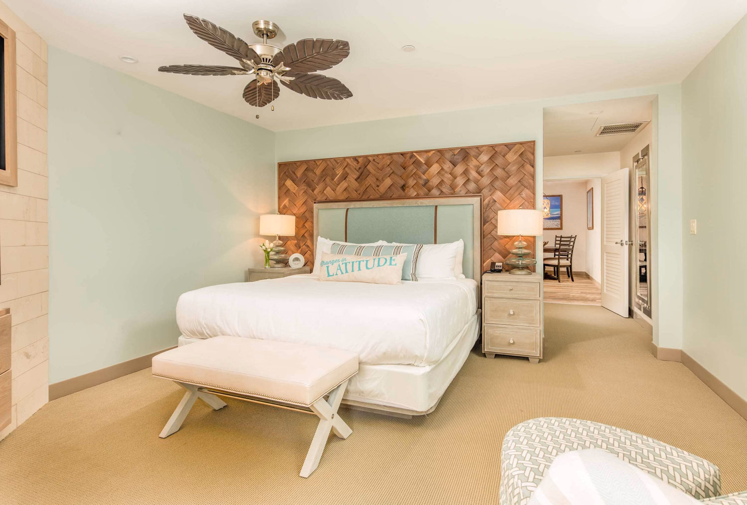 Bright bedroom with a woven headboard, white bed, and ceiling fan in a D&S Builders interior.