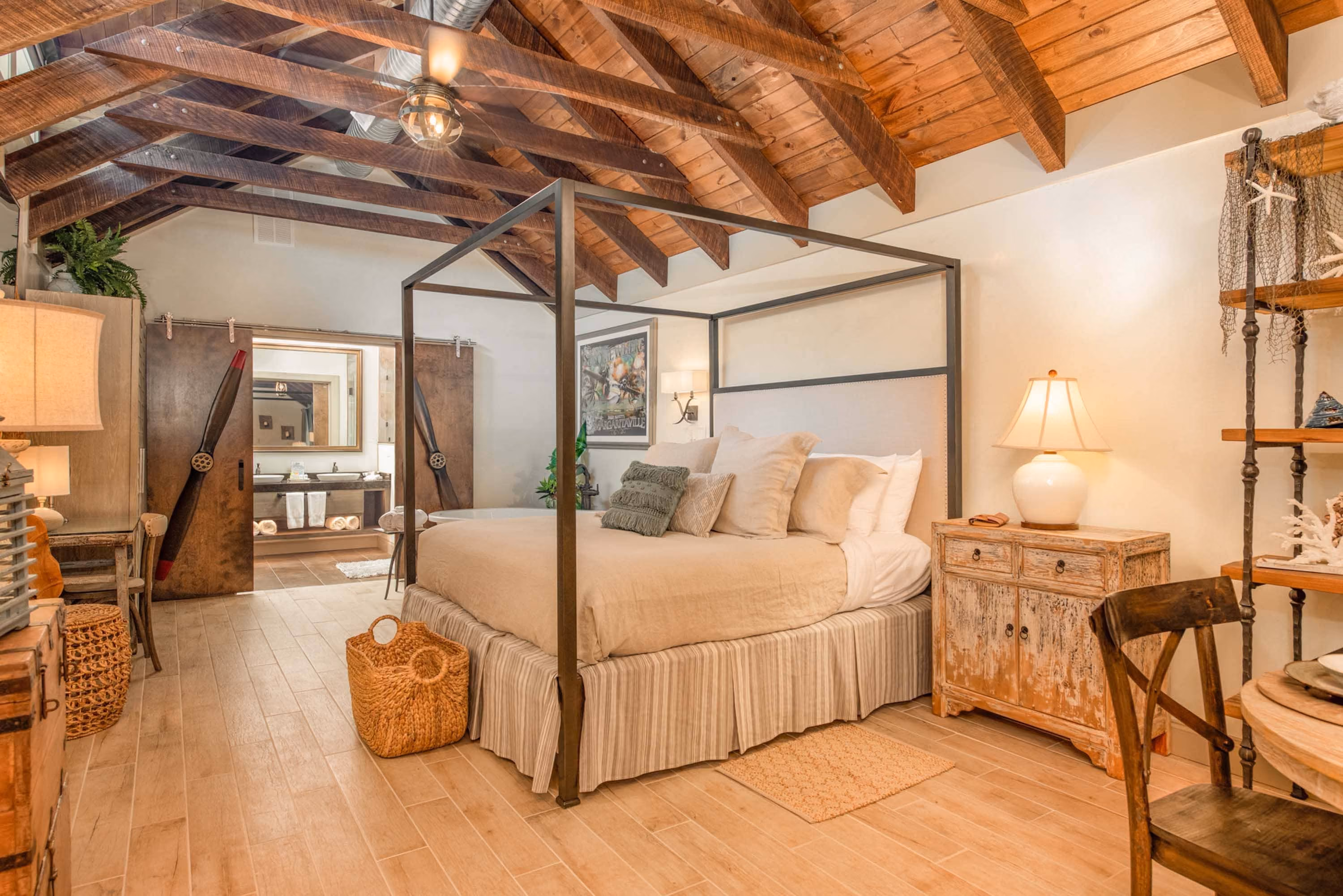 Rustic bedroom with a four-poster bed and exposed wood beams, styled for hospitality construction.