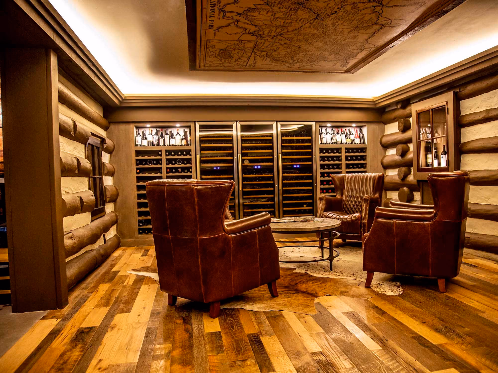 Rustic wine room with leather chairs, wood floors, and built-in wine storage by D&S Builders