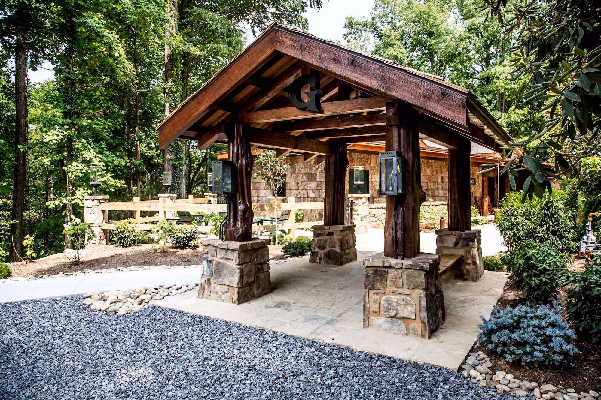 Rustic timber and stone entry pavilion at a wooded D&S Builders hospitality site
