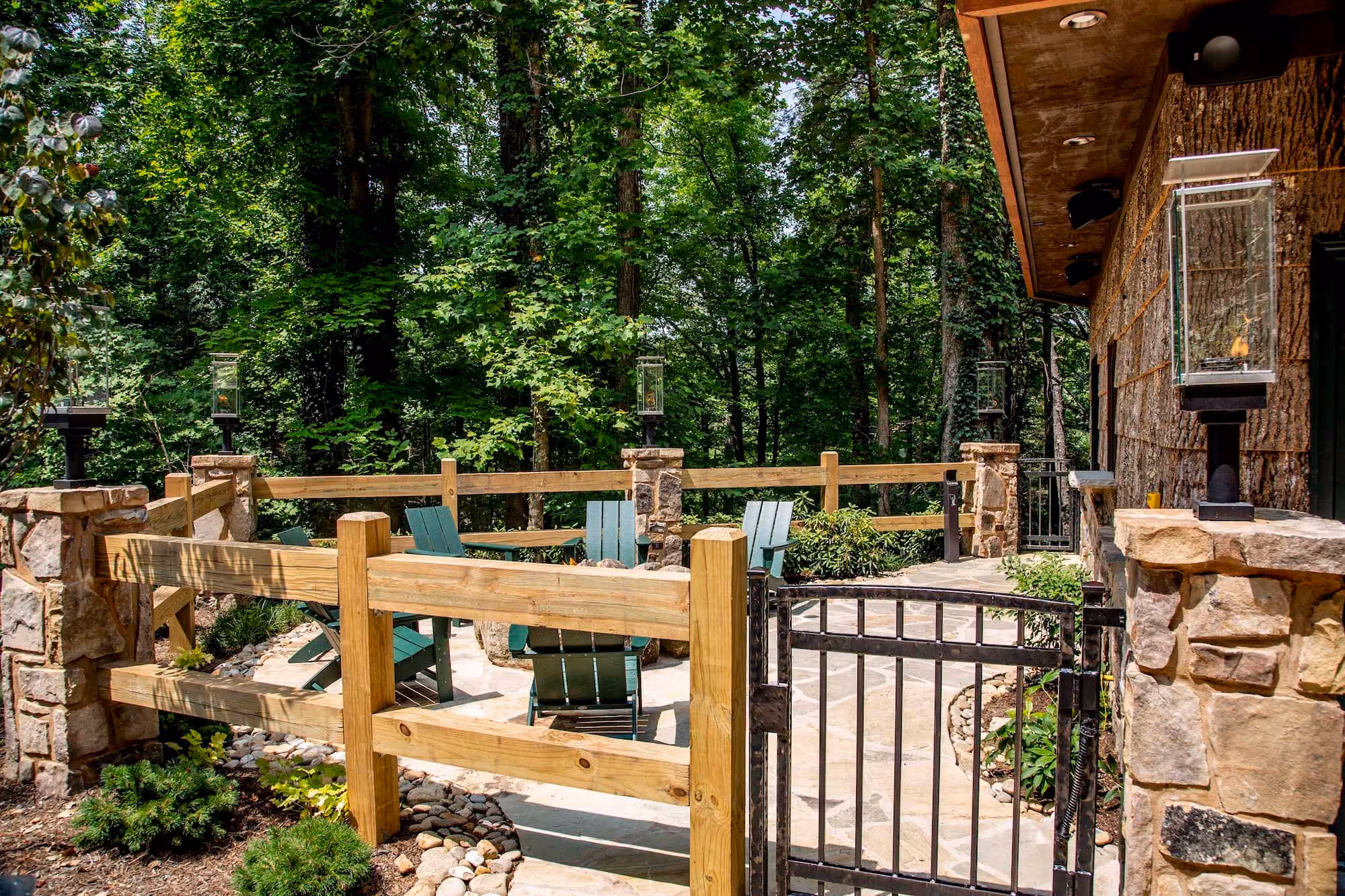Wooden-fenced patio with Adirondack chairs beside a wooded D&S Builders home