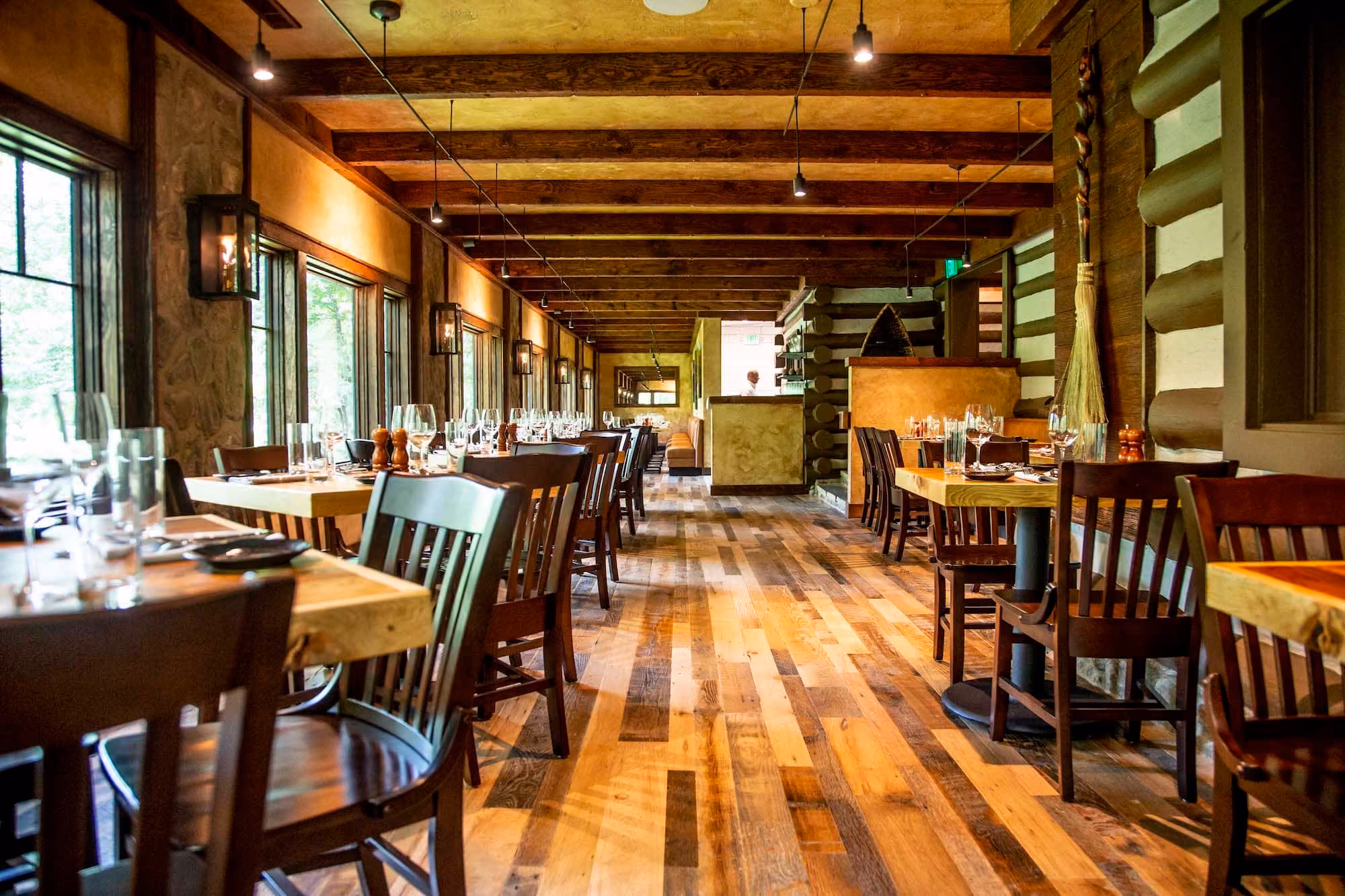 Rustic restaurant dining room with wooden tables, chairs, and exposed beam ceiling