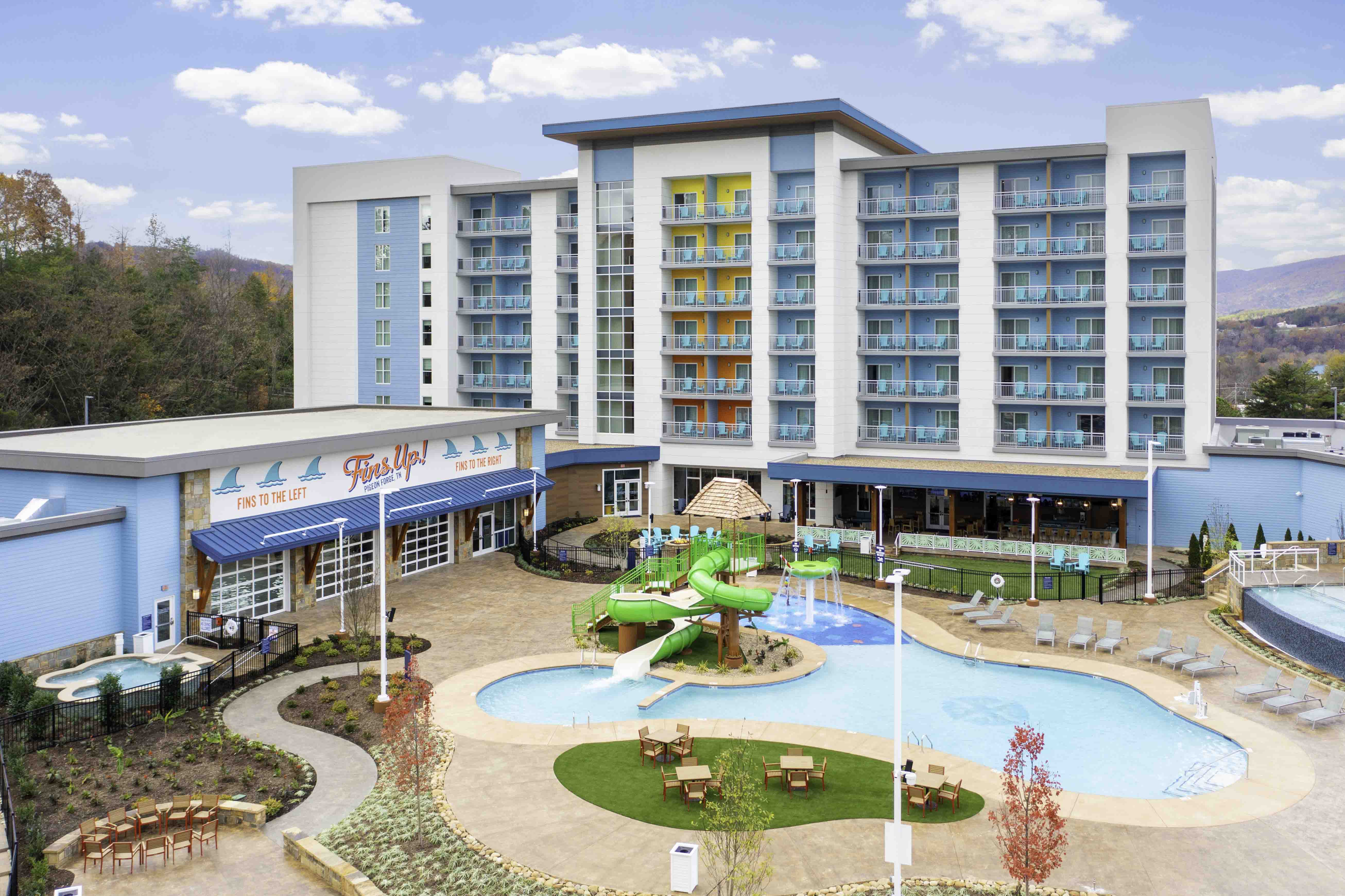 Modern hotel with pool, water slide, and balconies in a mountain setting