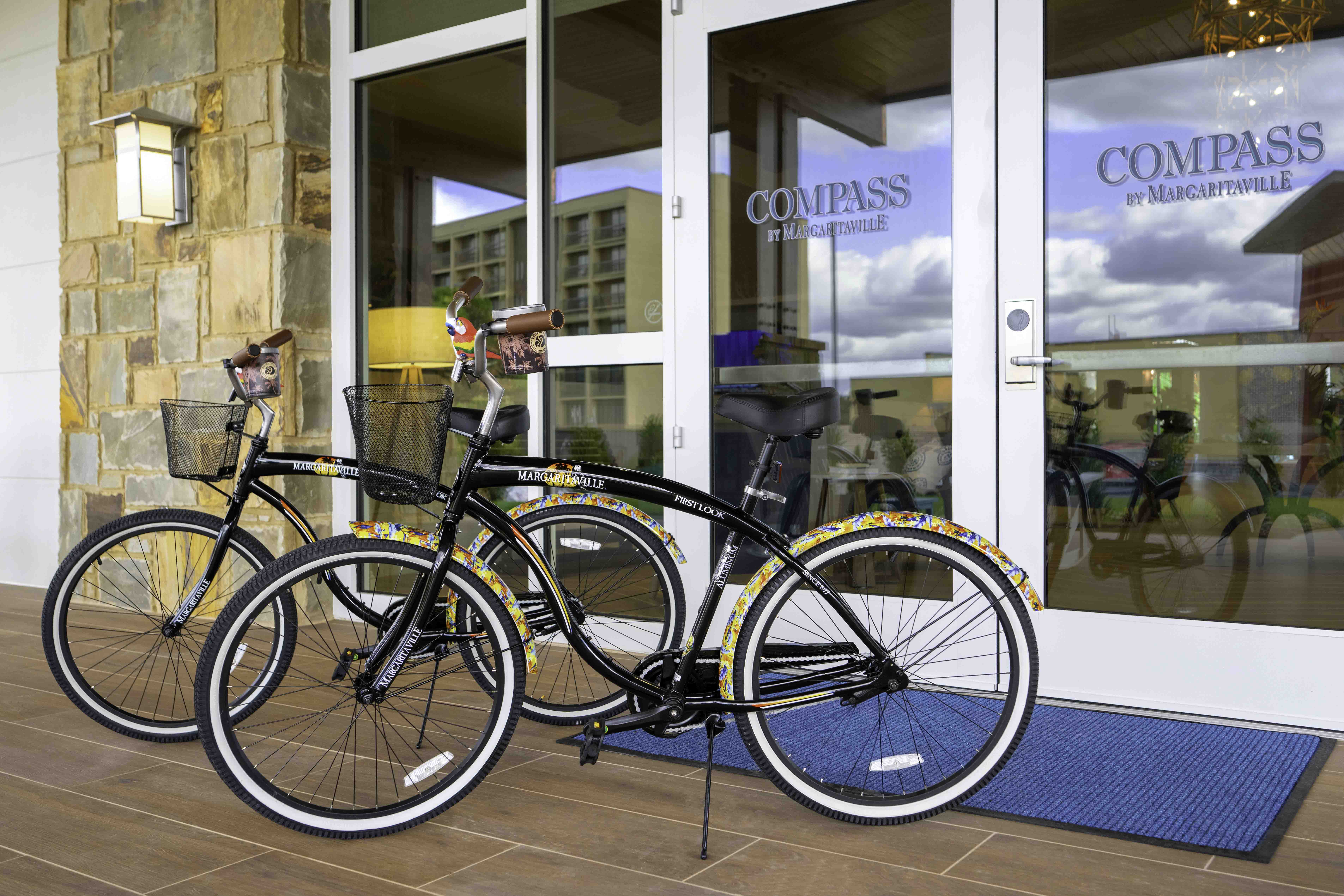Bicycles parked outside a hotel entrance with glass doors and stone walls