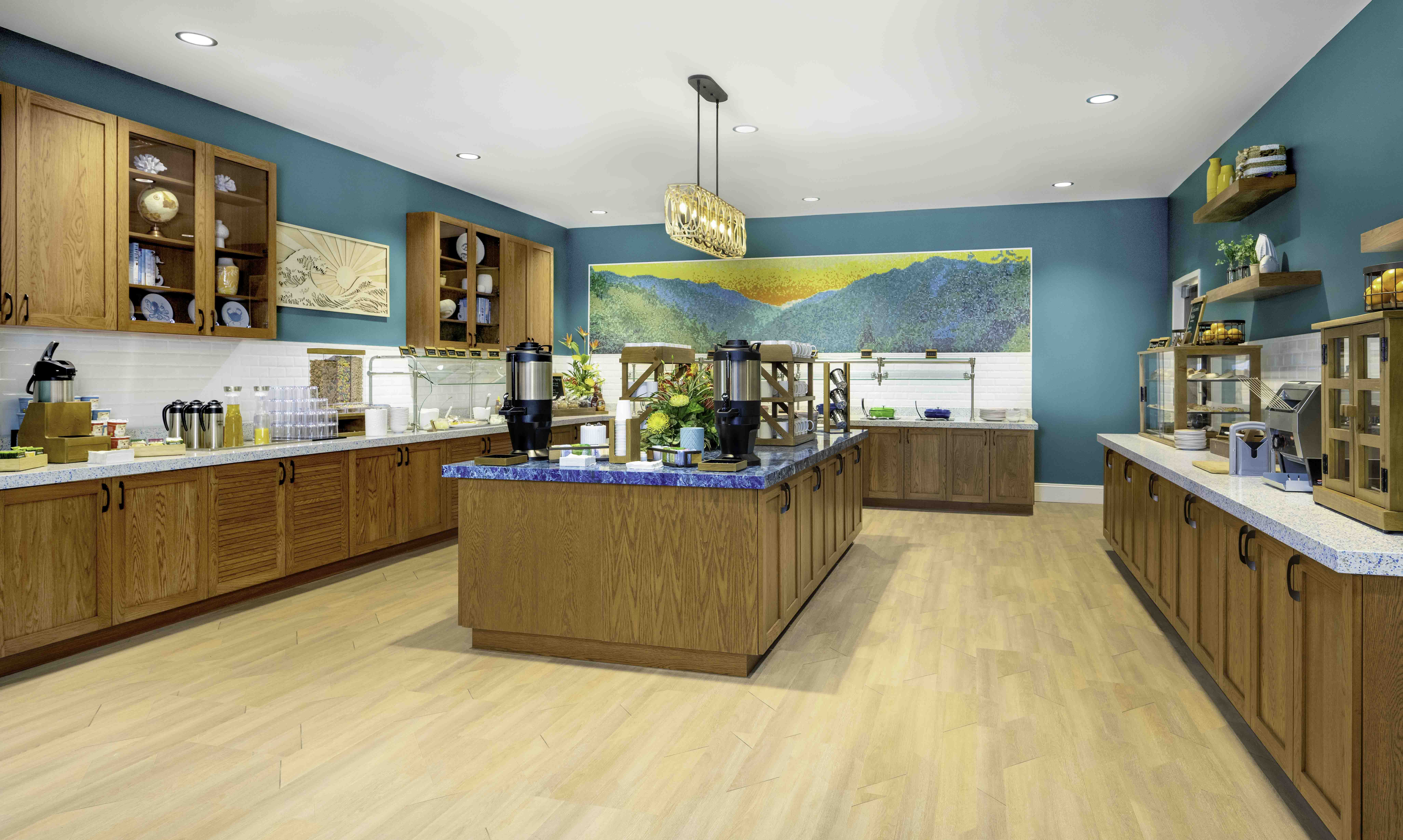 Bright hospitality breakfast buffet with teal walls and wood cabinetry