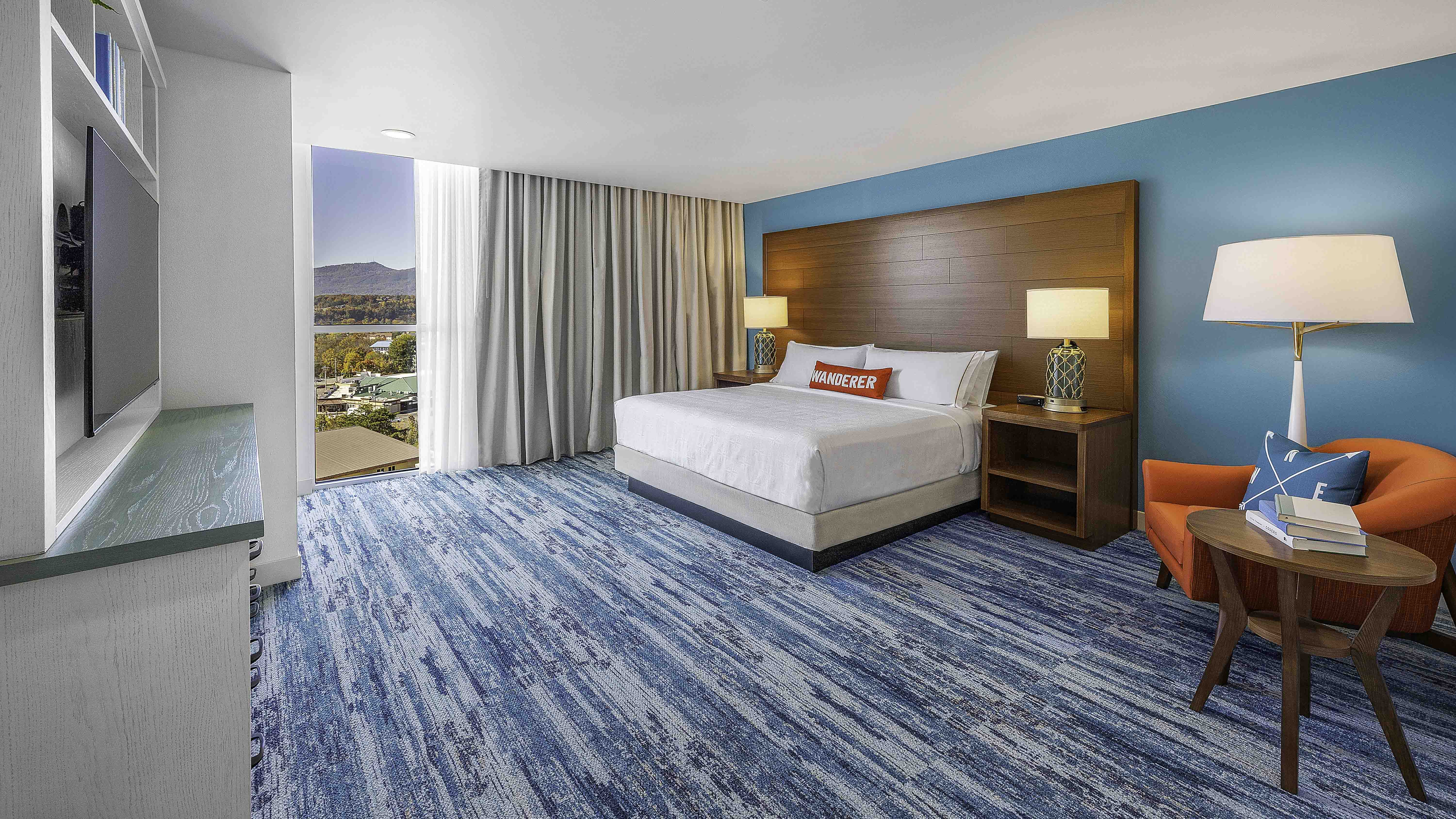 Modern hotel room with blue carpet, king bed, and mountain view in Knoxville