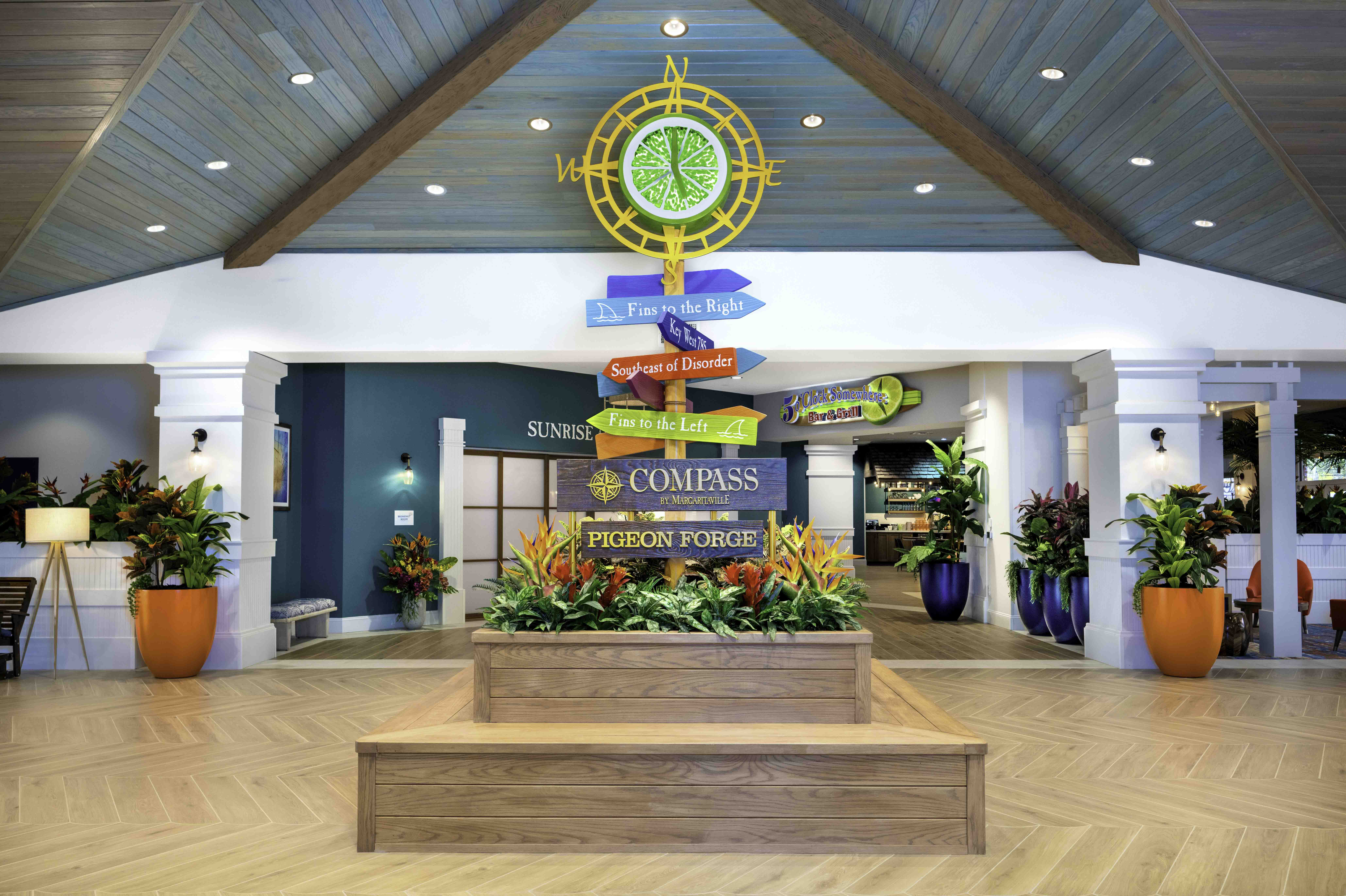 Bright hospitality lobby with a compass sign and tropical plants in Pigeon Forge