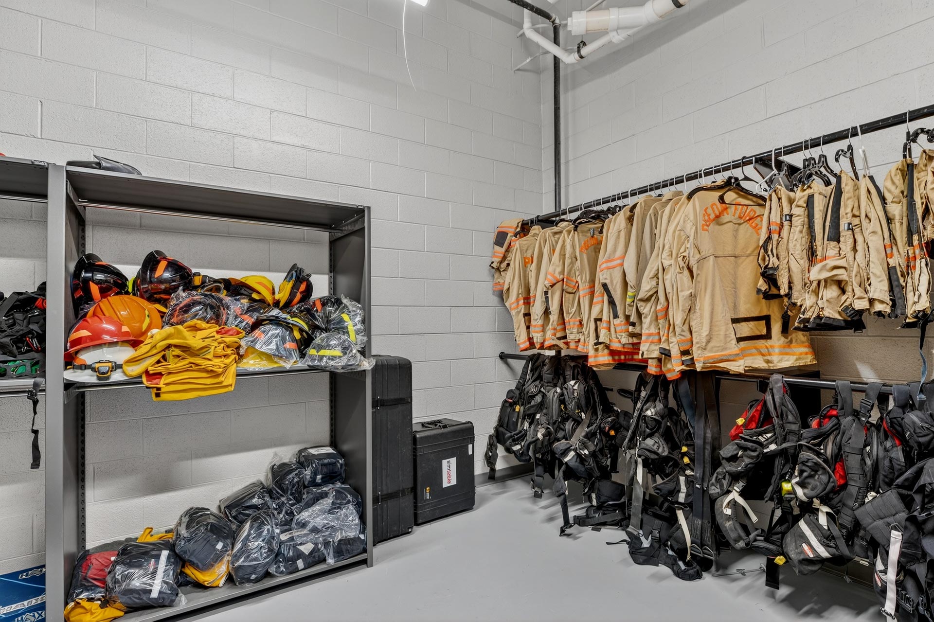 Firefighter gear and helmets stored on shelves and racks in a clean equipment room