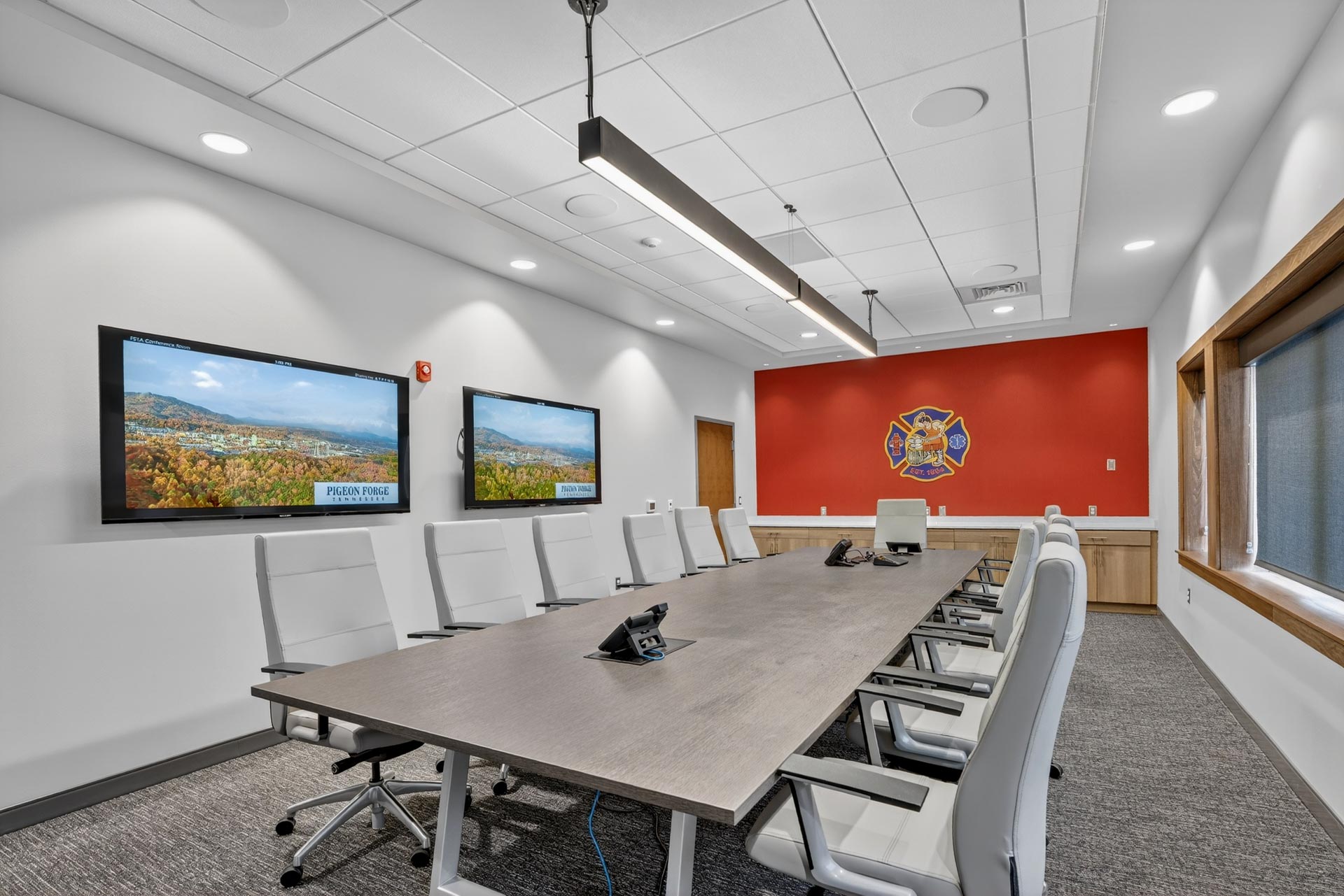Modern conference room with long table, wall screens, and Pigeon Forge display at D&S Builders