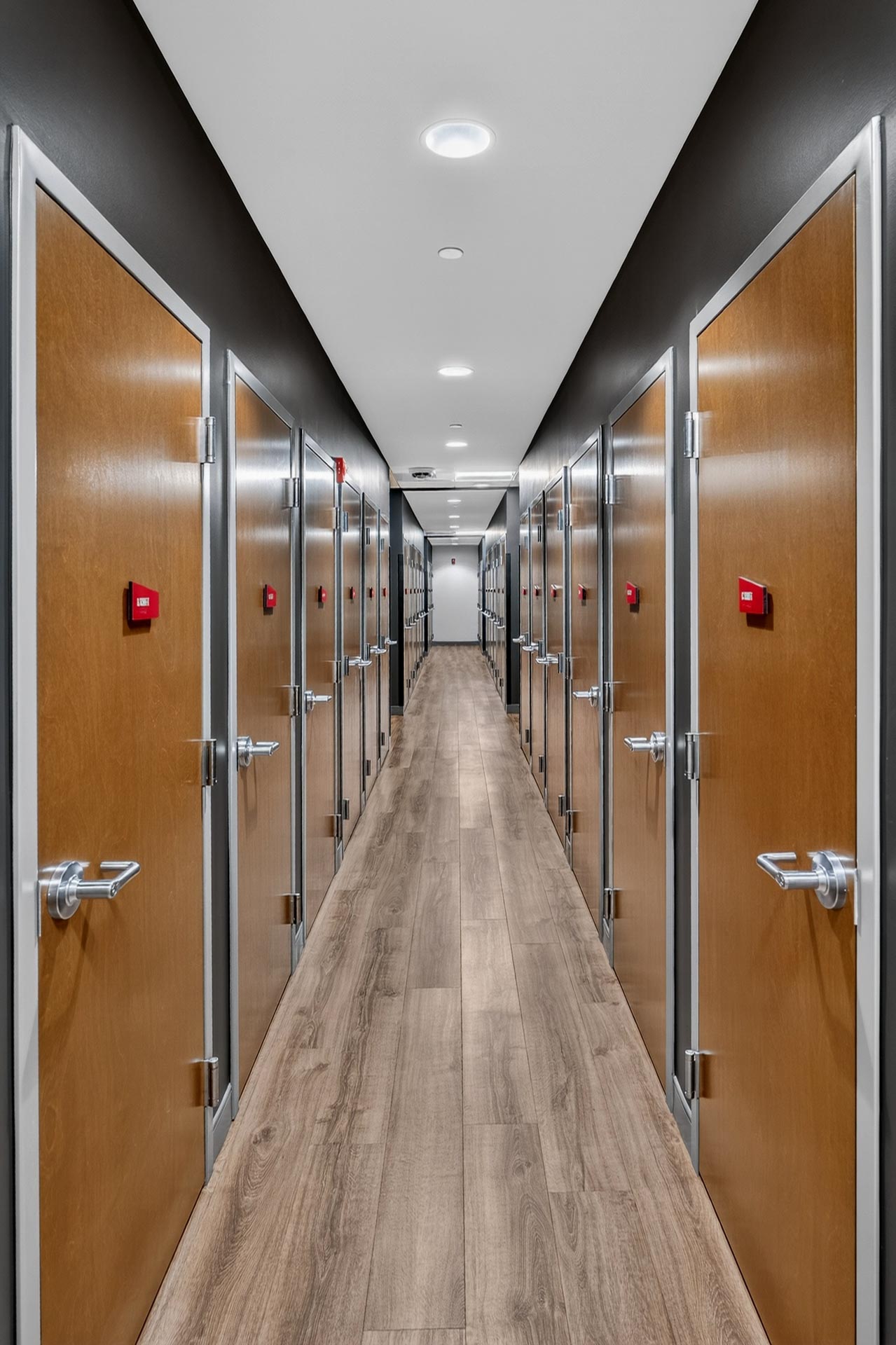 Long hallway with wood doors and recessed lighting in a D&S Builders hospitality construction project