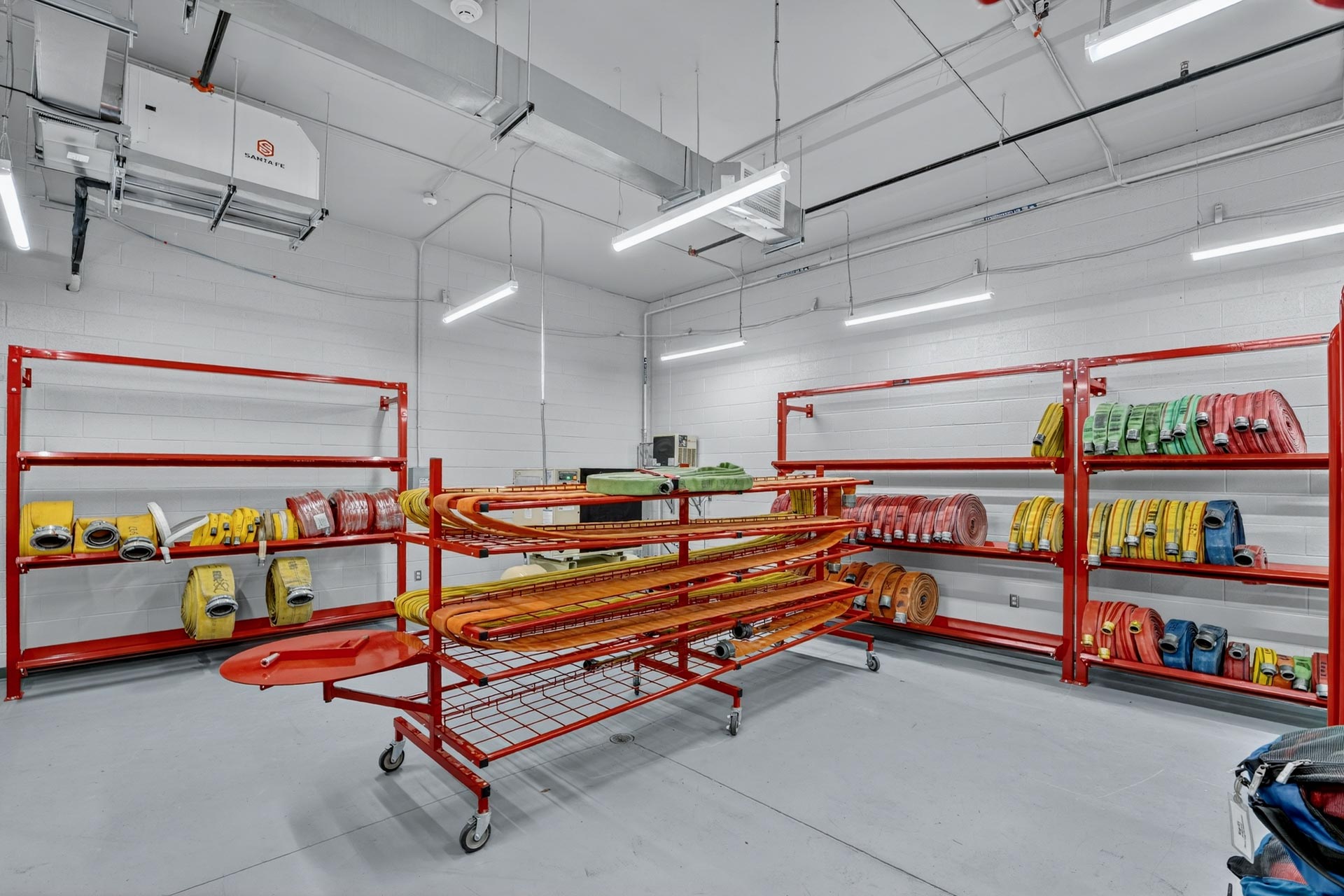 Fire hose storage room with red shelving and coiled hoses in a D&S Builders facility