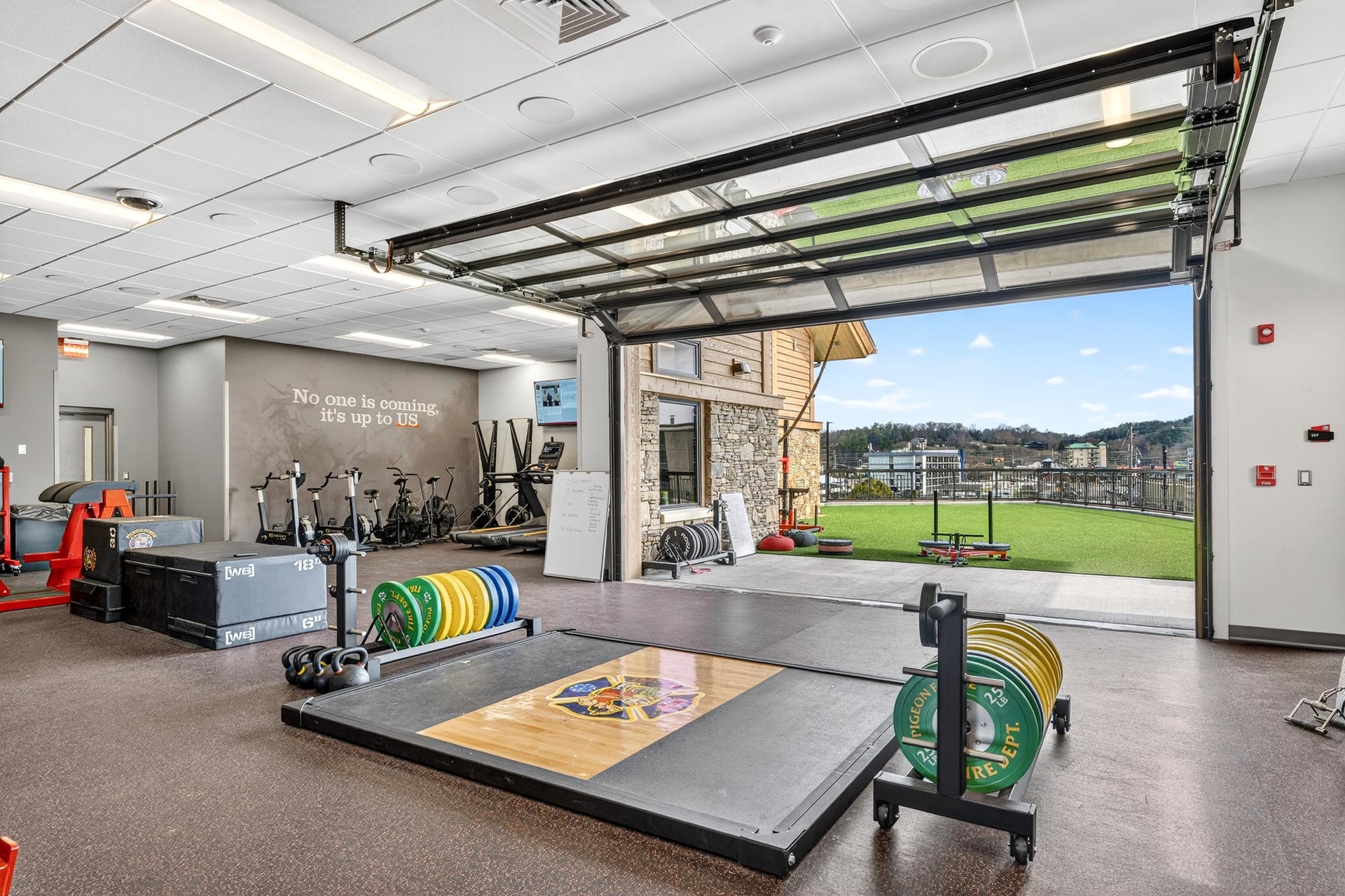 Hospitality construction gym with open garage door and weightlifting equipment