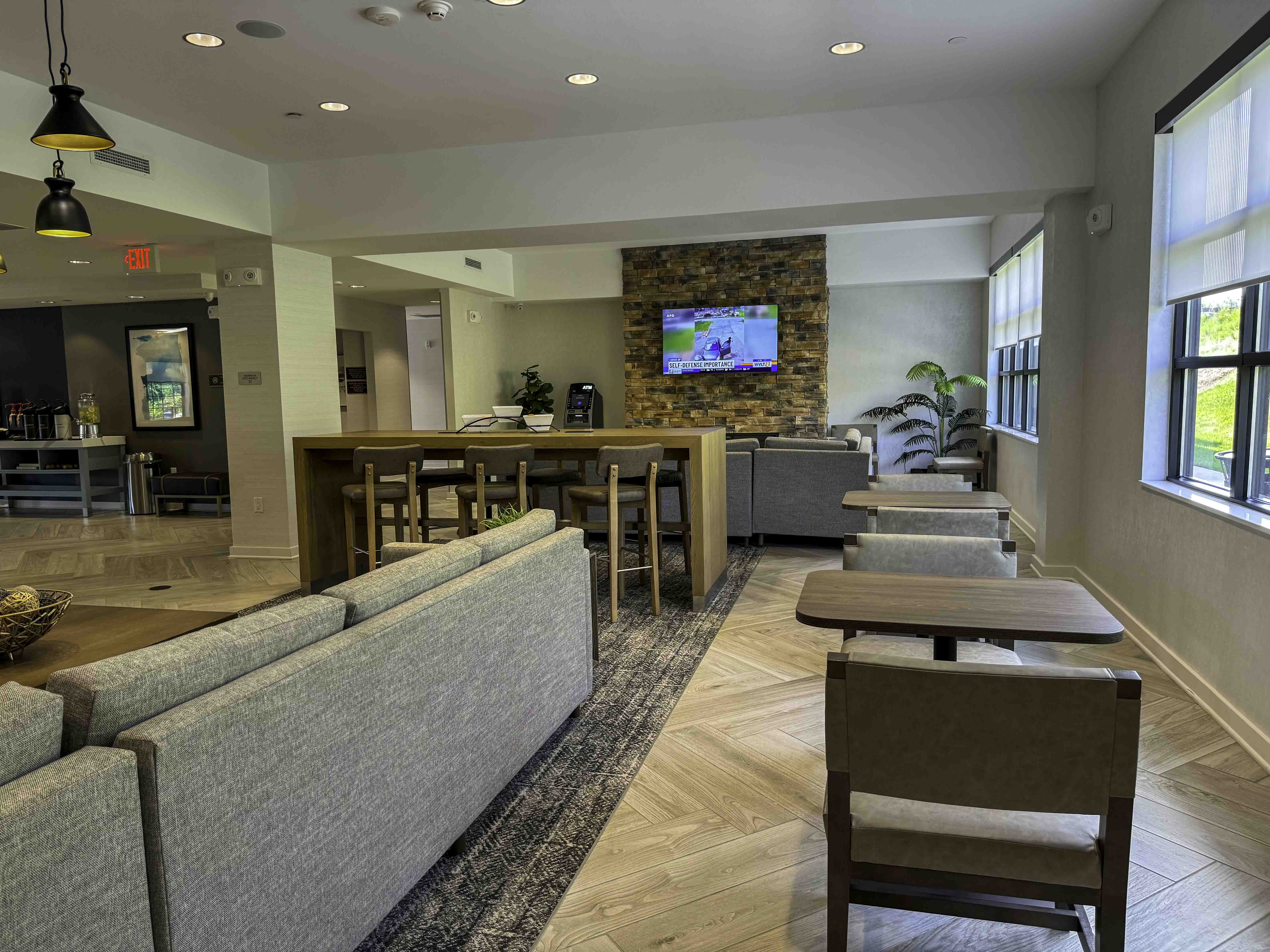 Modern hotel lobby seating area with sofas, tables, and a stone TV wall