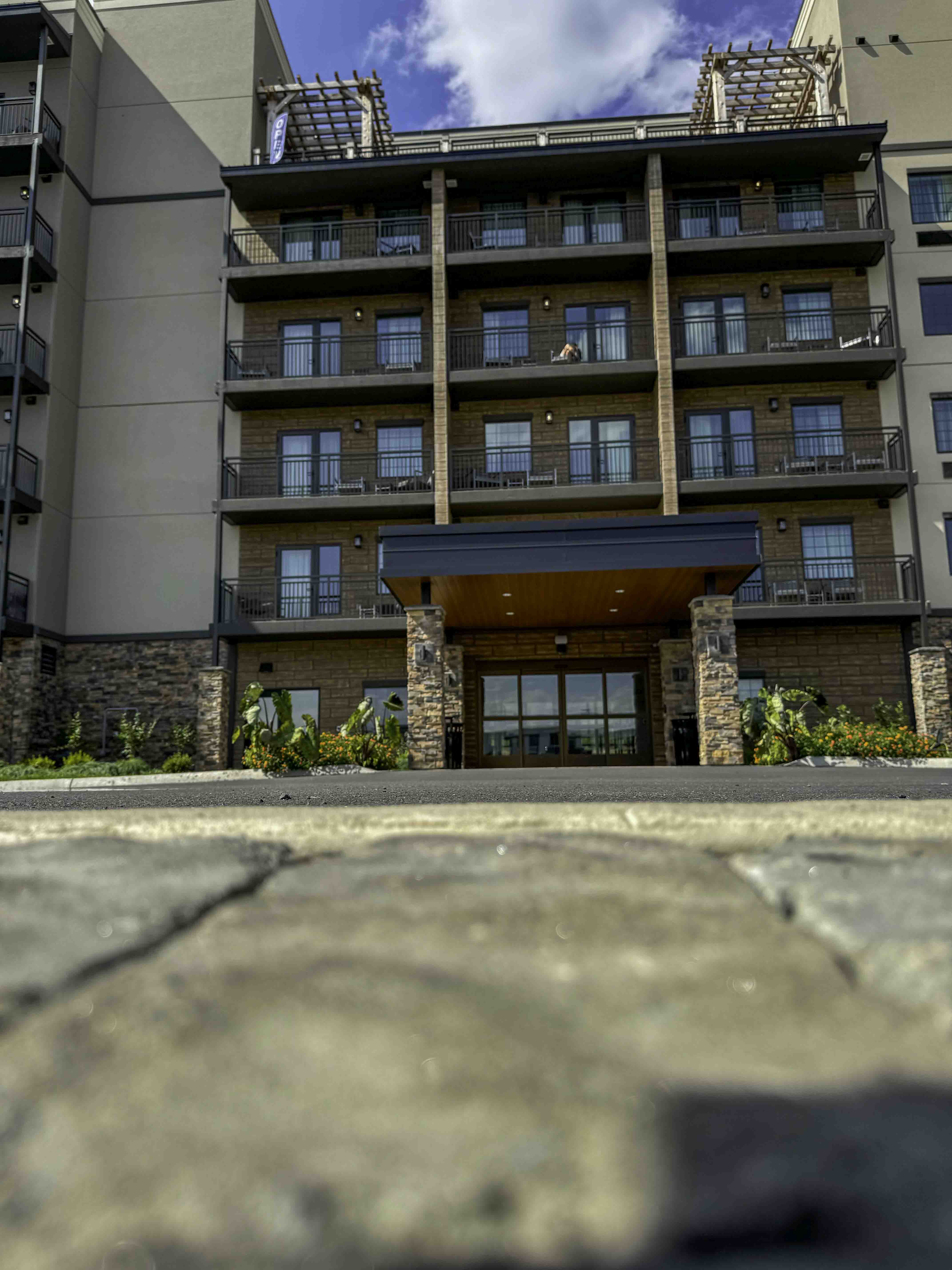 Multi-story hotel exterior with balconies and a covered entrance, viewed from ground level