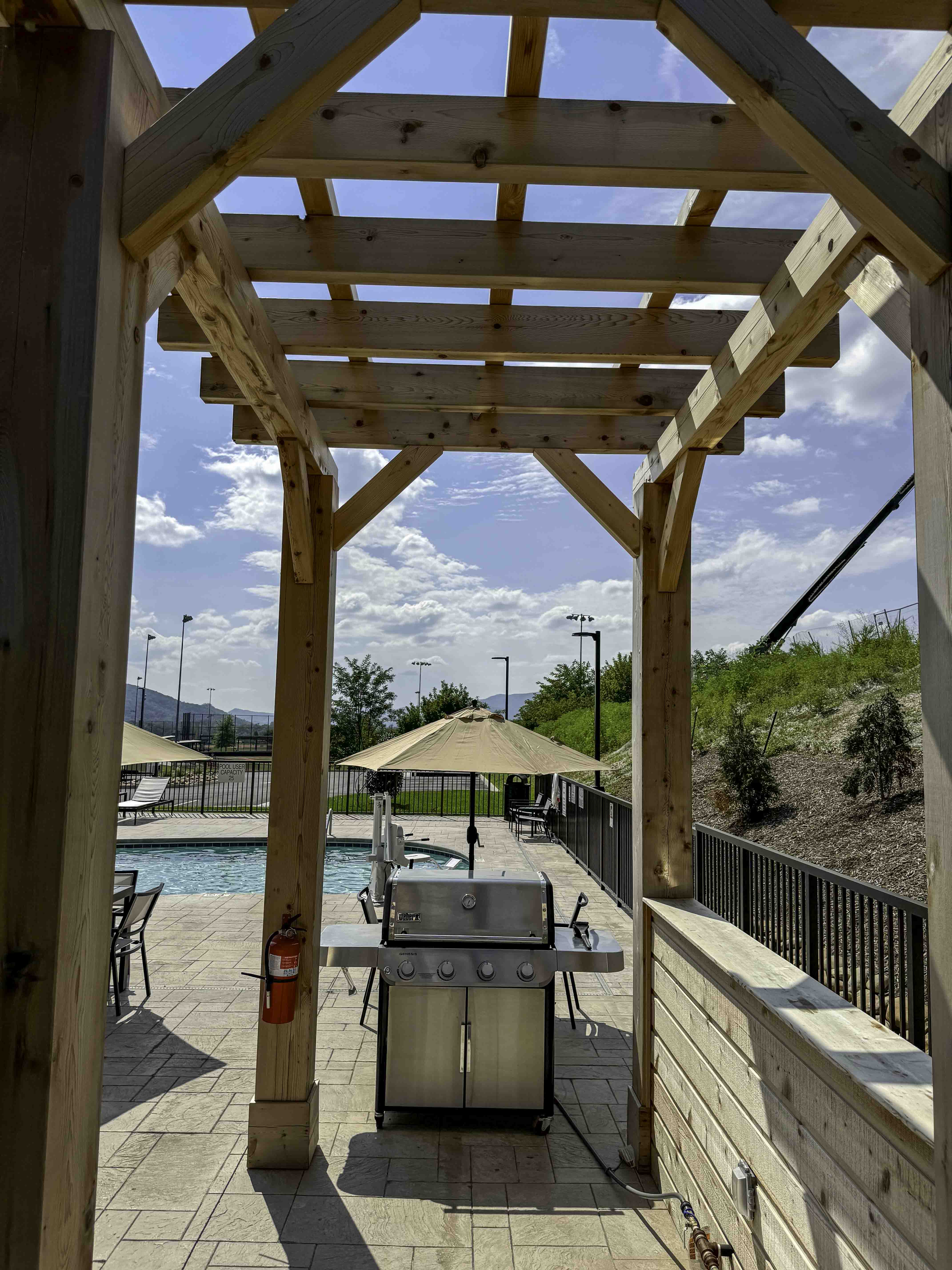 Wooden pergola over a poolside grill area at a hospitality construction site.