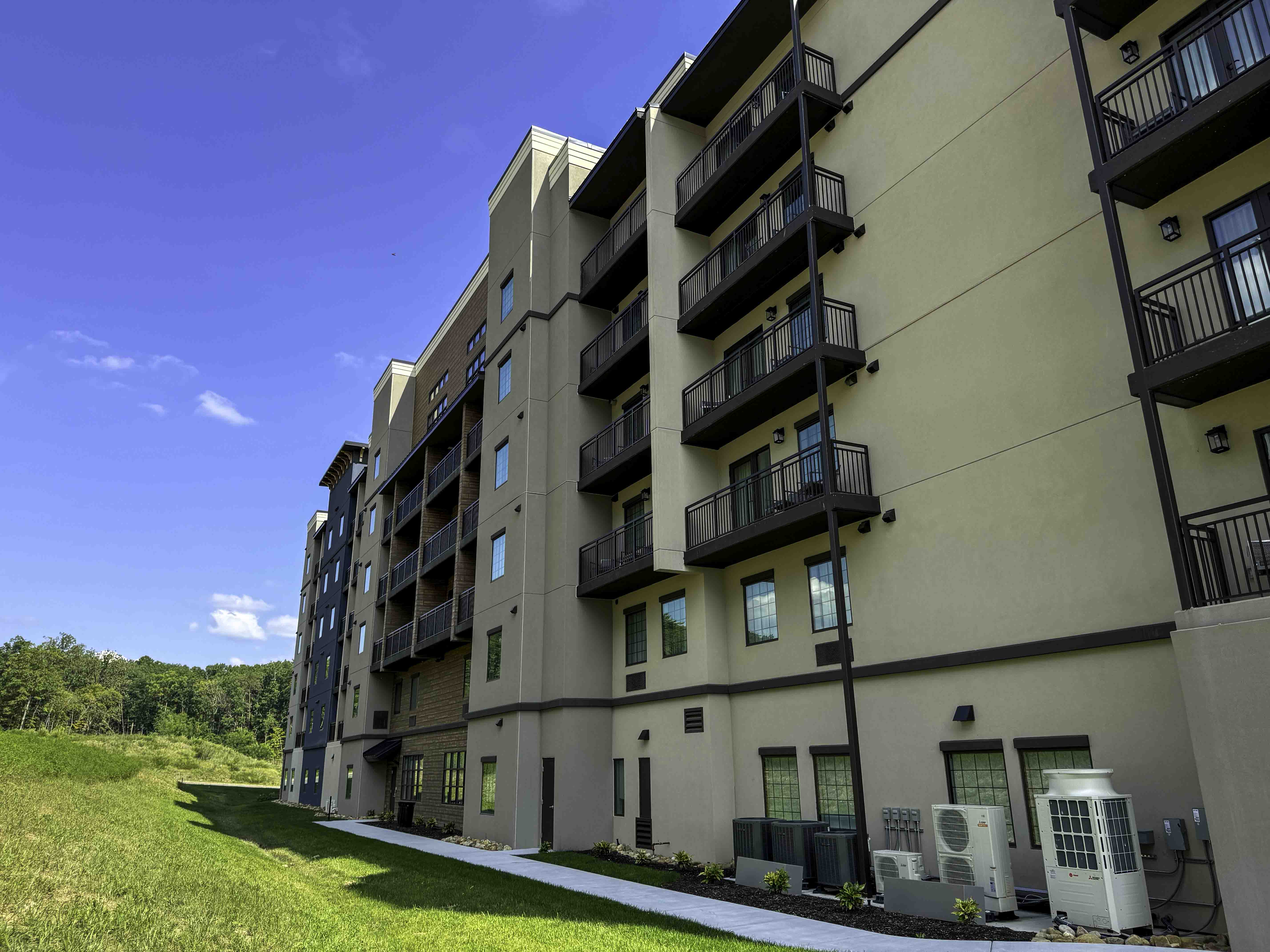 Multi-story hospitality building with balconies and landscaped grounds under a blue sky