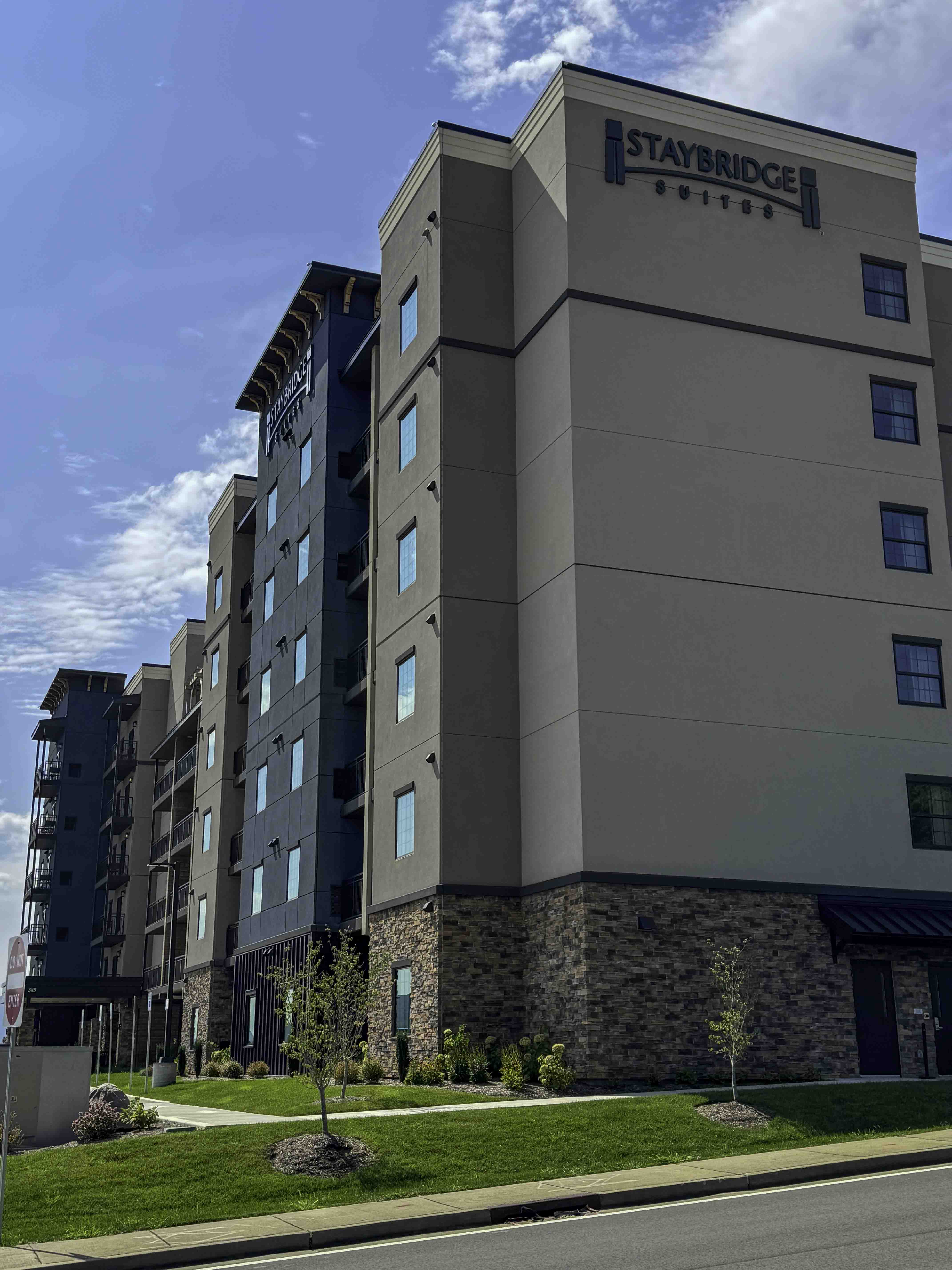 Staybridge Suites hotel exterior with stone base and landscaped lawn