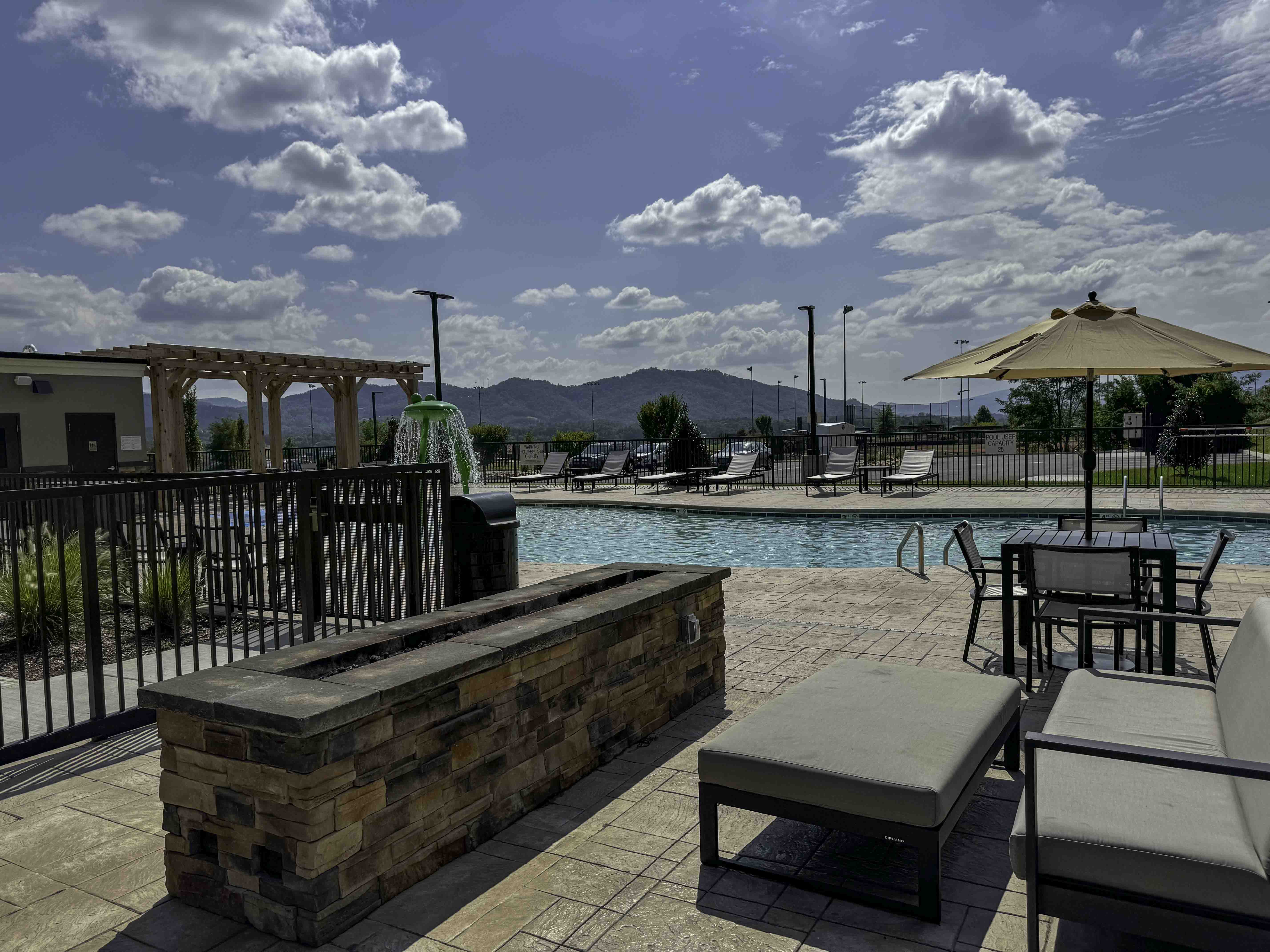 Outdoor pool patio with lounge seating, umbrellas, and mountain views at a hospitality property