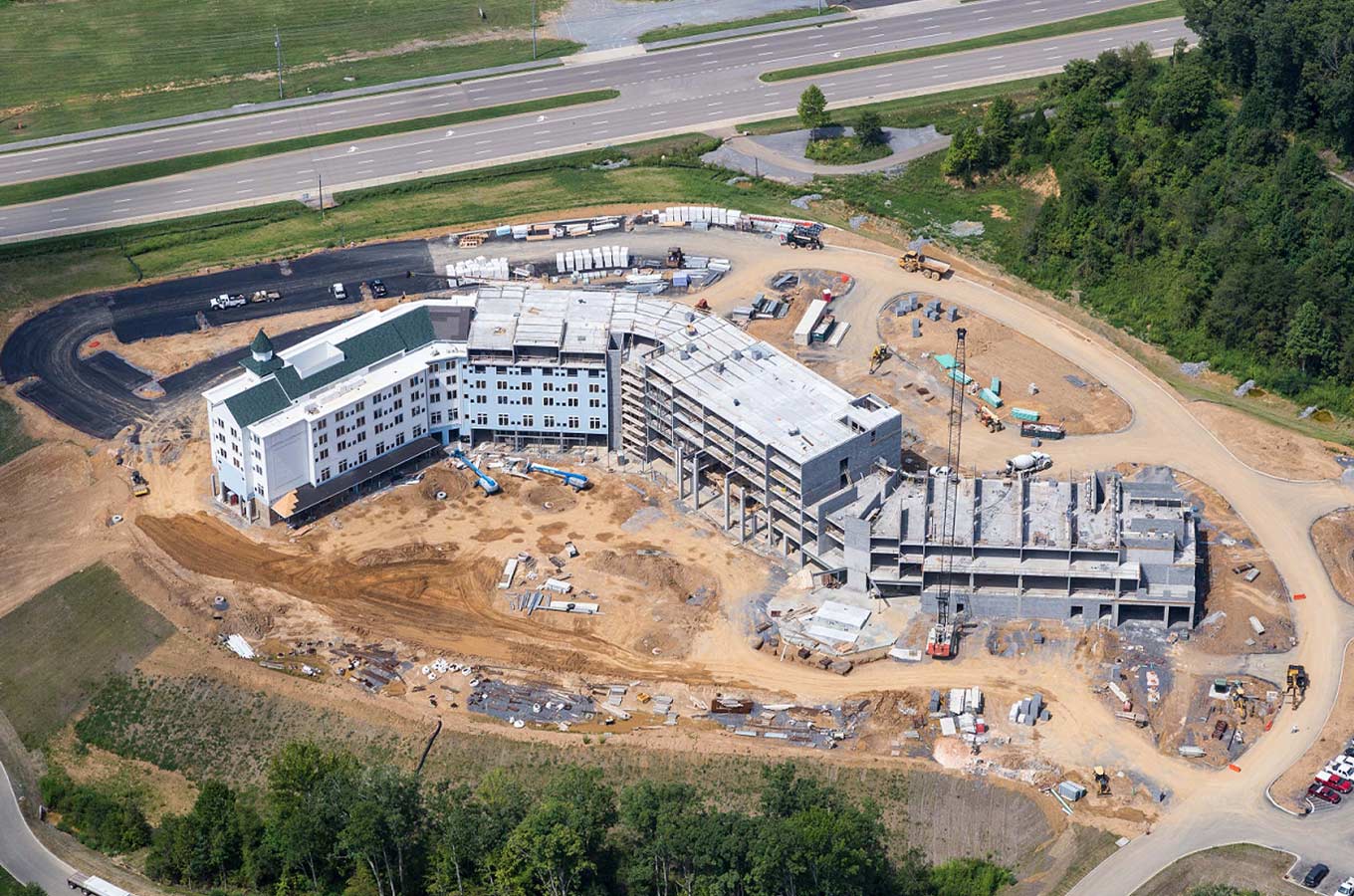 Aerial view of a large hotel construction site with multiple building wings and surrounding earthwork