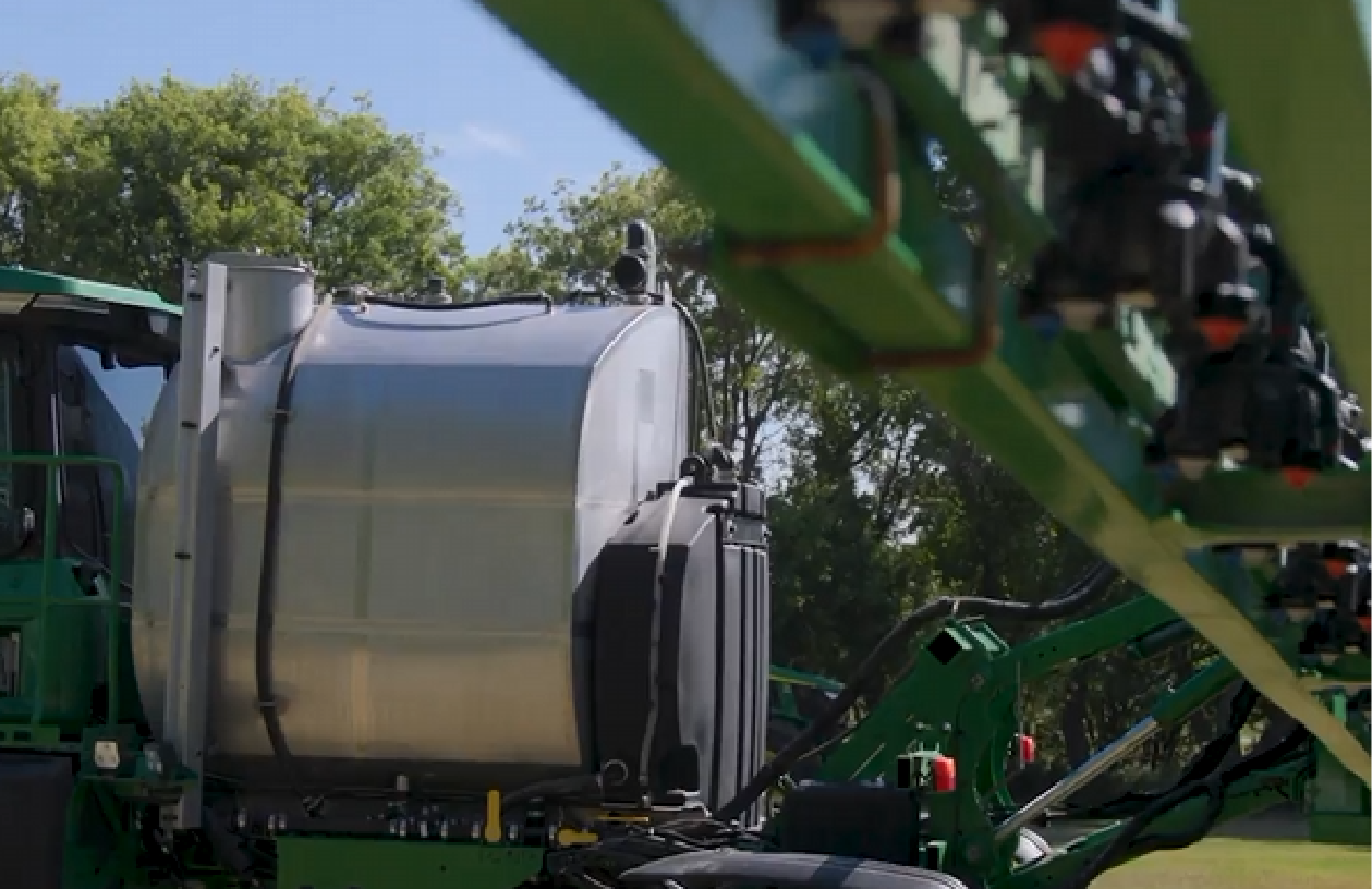 Tractor in a field with a modified sprayer attachment