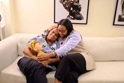 An older woman hugging her daughter while holding Joy