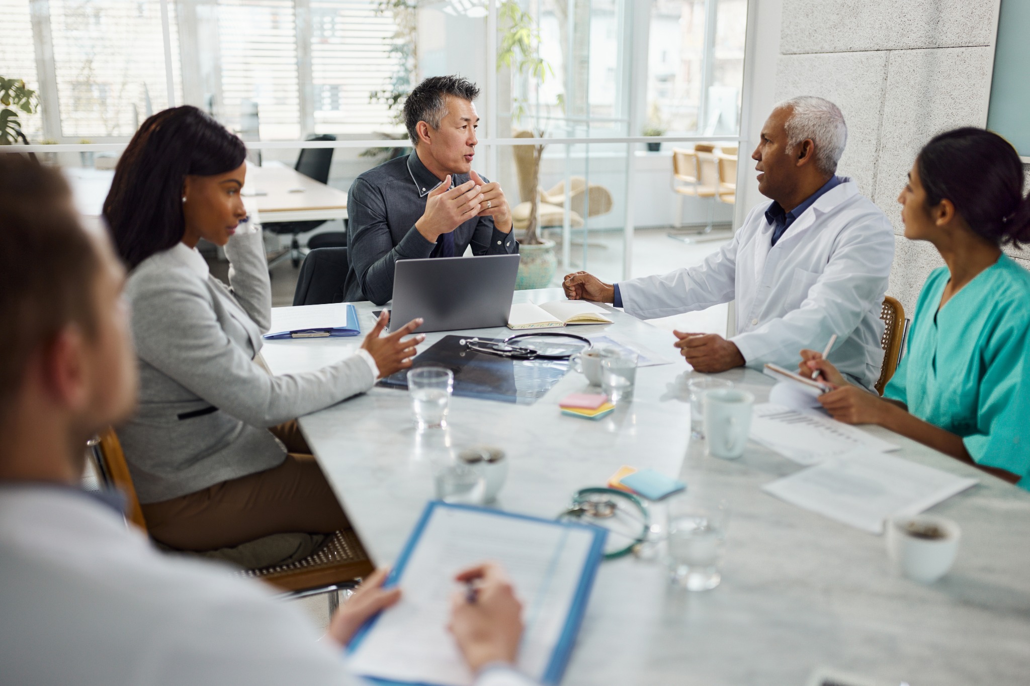 Healthcare professionals and organizational leaders meeting around a conference table.